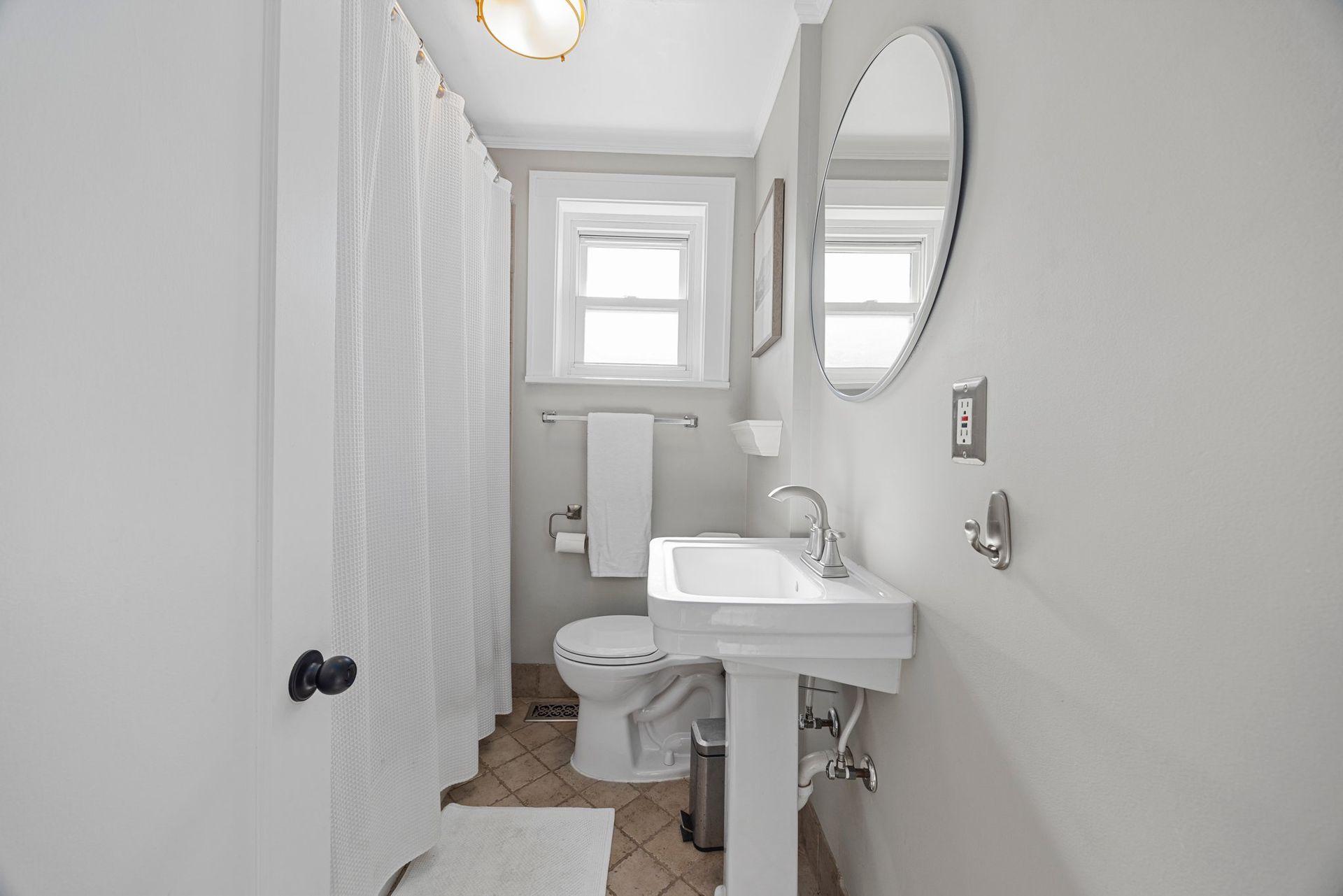 A bathroom with a toilet , sink , mirror and shower curtain.
