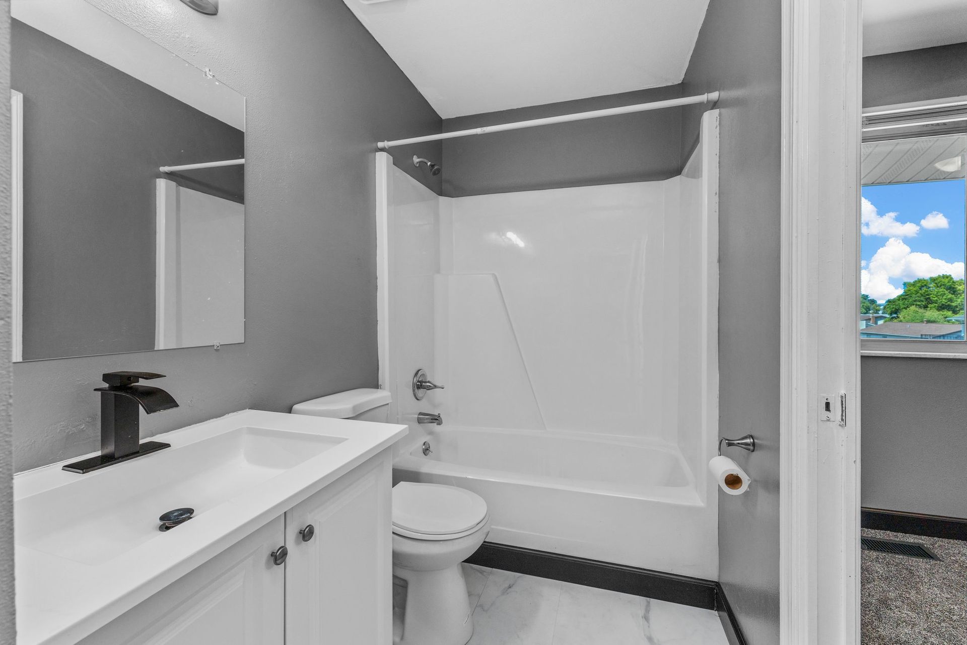 A bathroom with a sink , toilet , tub and mirror.