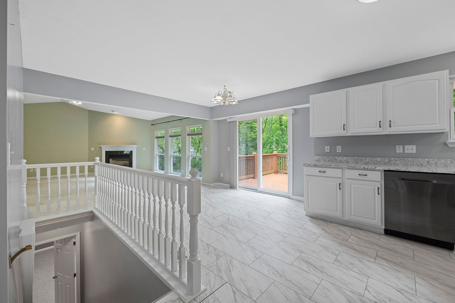 An empty kitchen with white cabinets and a black dishwasher.