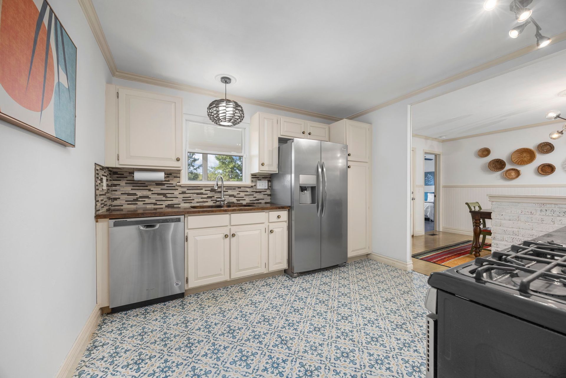 Kitchen with white cabinets, stainless steel appliances, blue patterned floor.