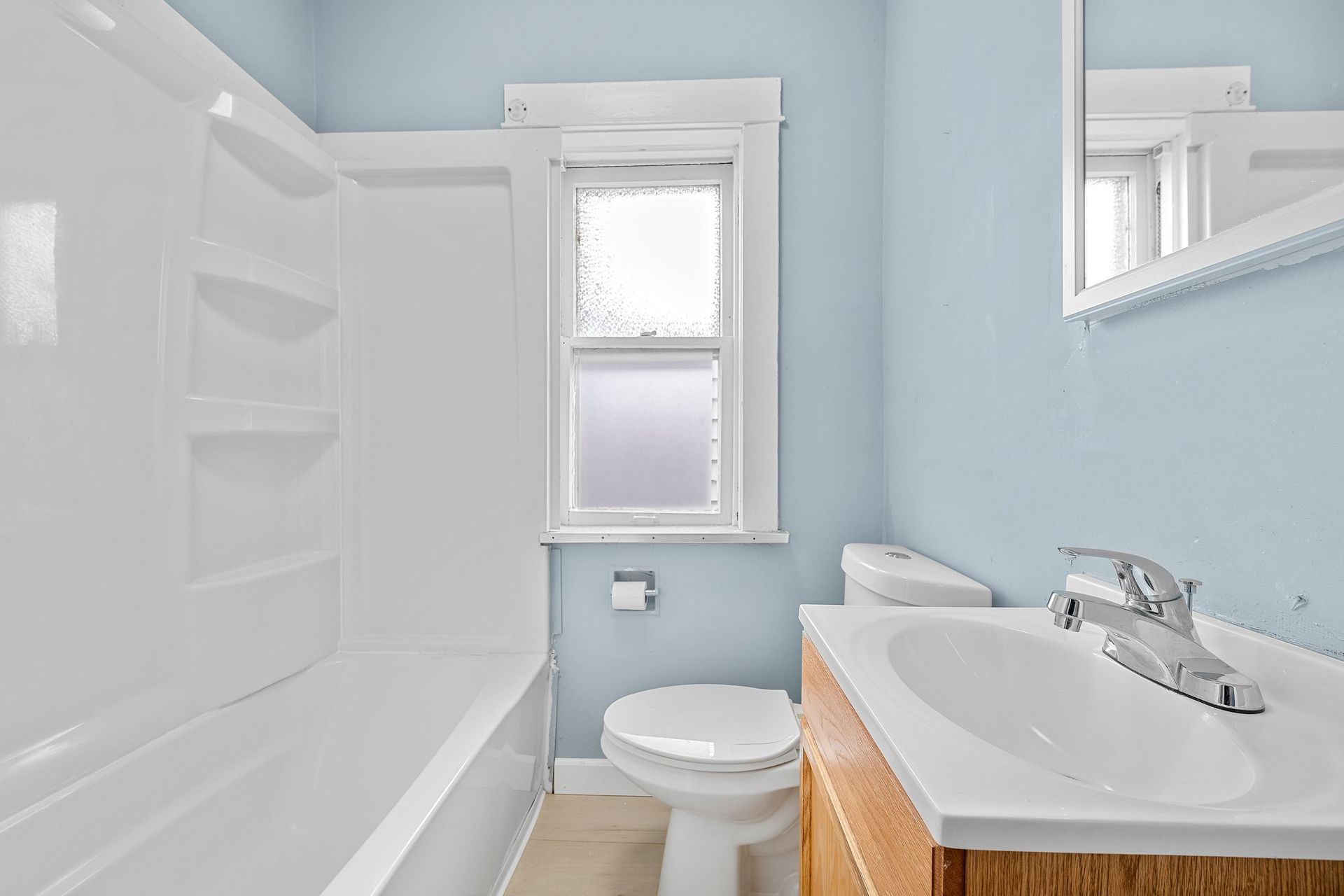 A bathroom with blue walls , a toilet , sink and bathtub.