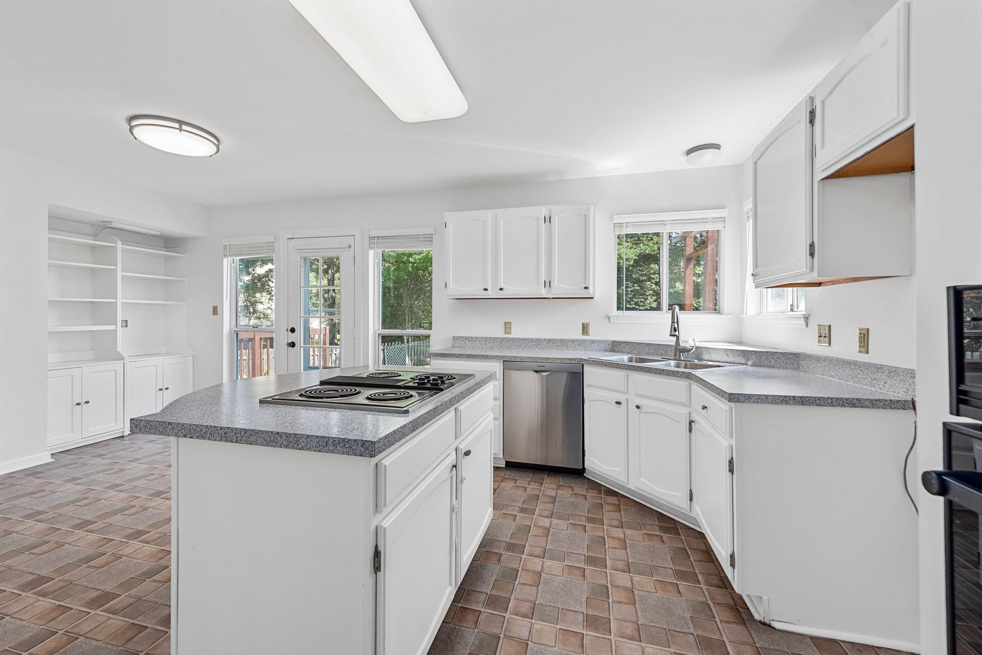 A kitchen with white cabinets , granite counter tops , stainless steel appliances and a large island.