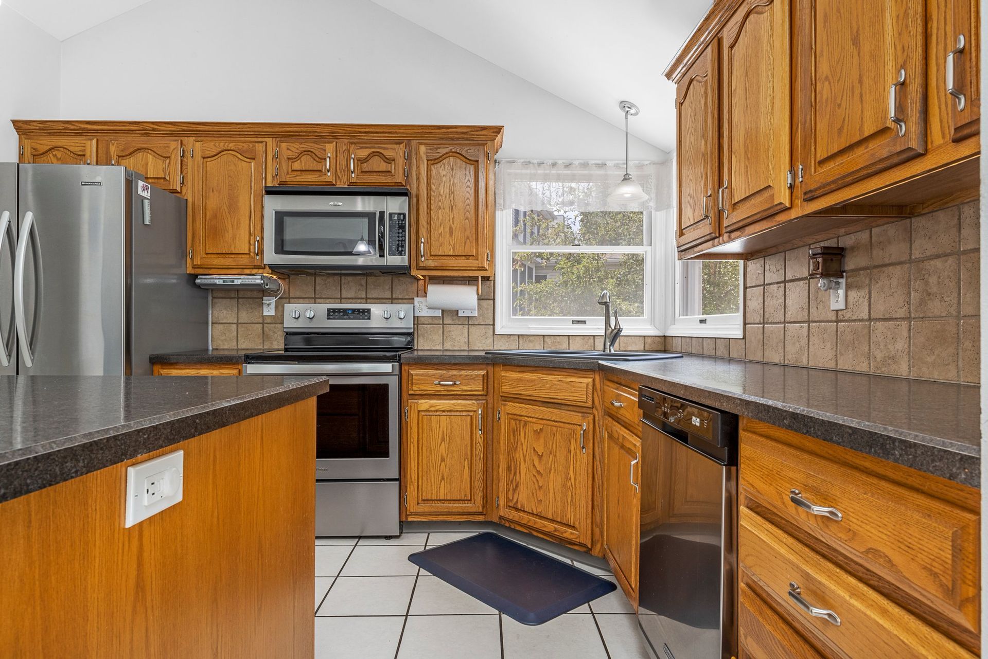 A kitchen with wooden cabinets , stainless steel appliances and granite counter tops.