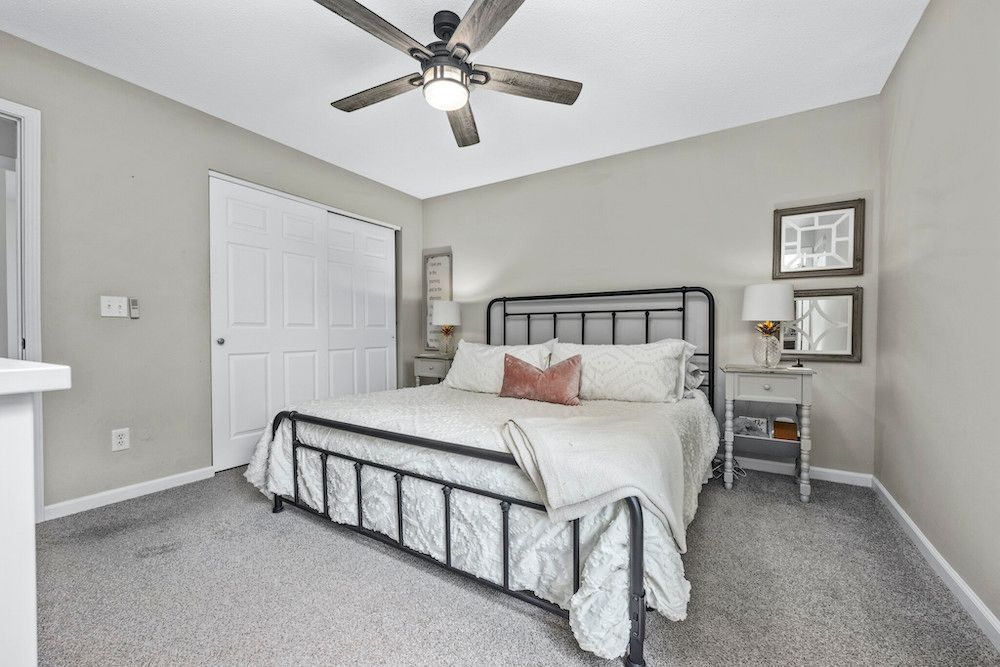 A bedroom with a king size bed and a ceiling fan.