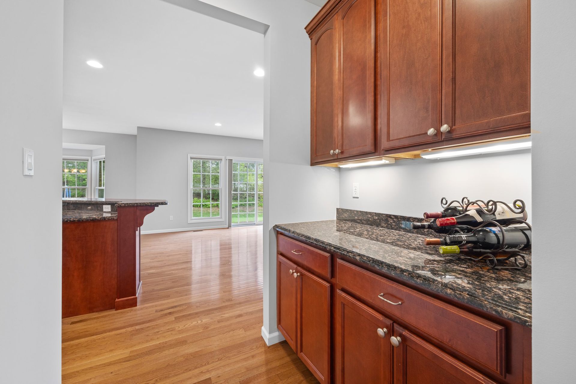 A kitchen with wooden cabinets and granite counter tops and a wine rack on the counter.