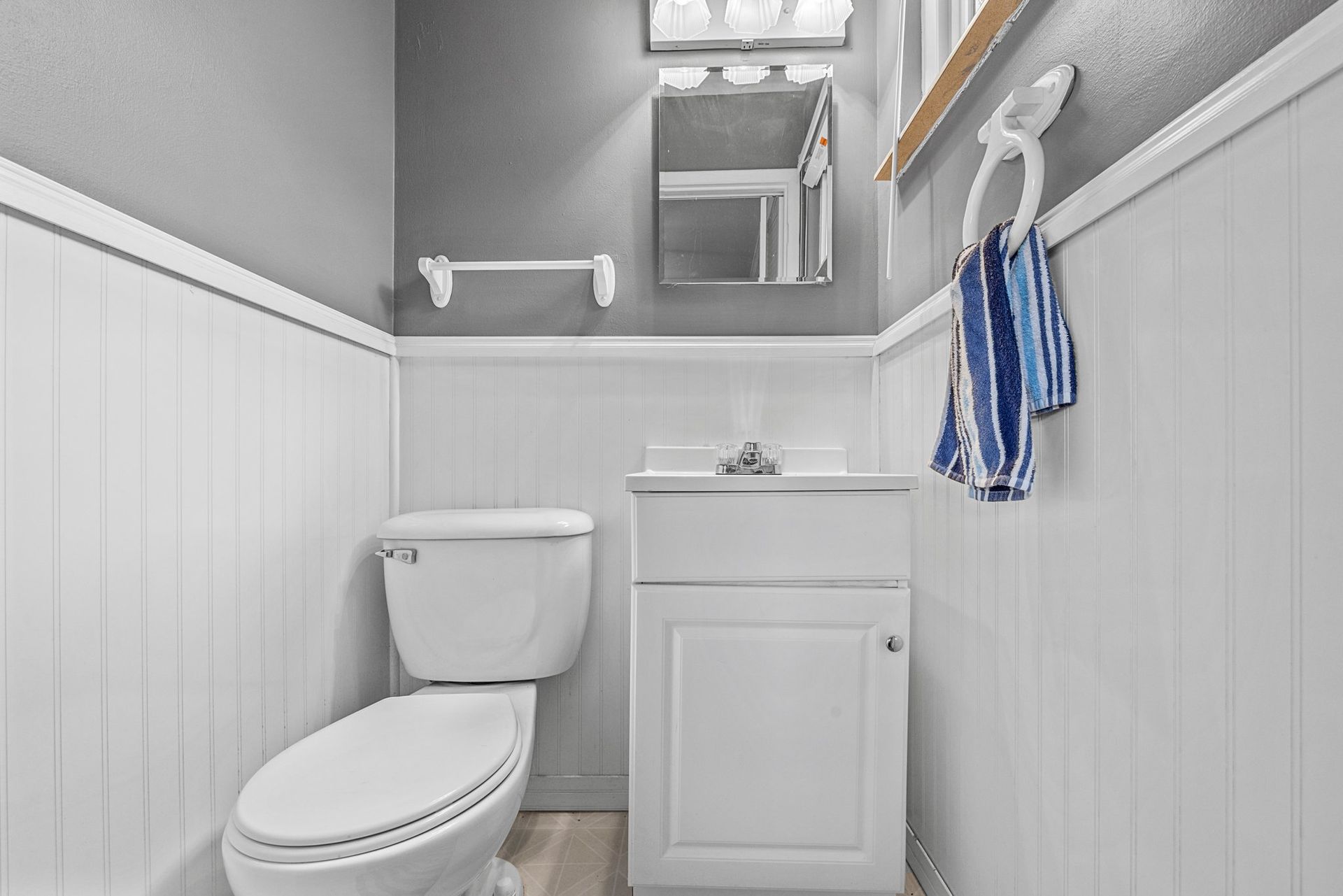 A bathroom with a toilet , sink and mirror.