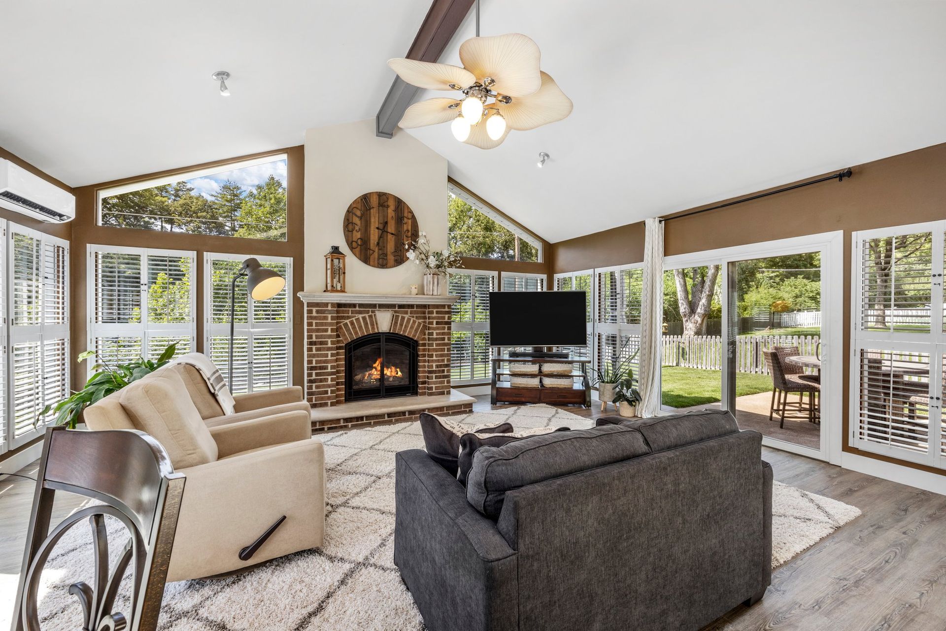 A living room with a couch , chair , television and fireplace.