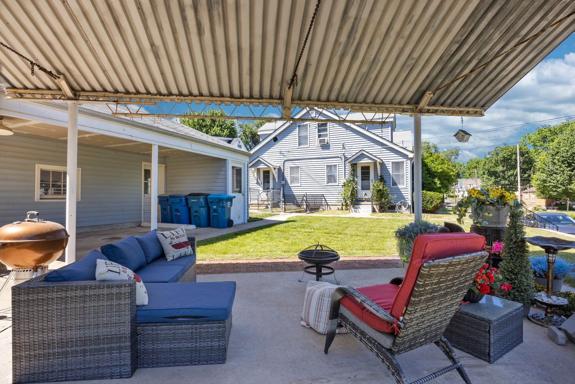 There is a patio with a couch and chairs under a canopy.