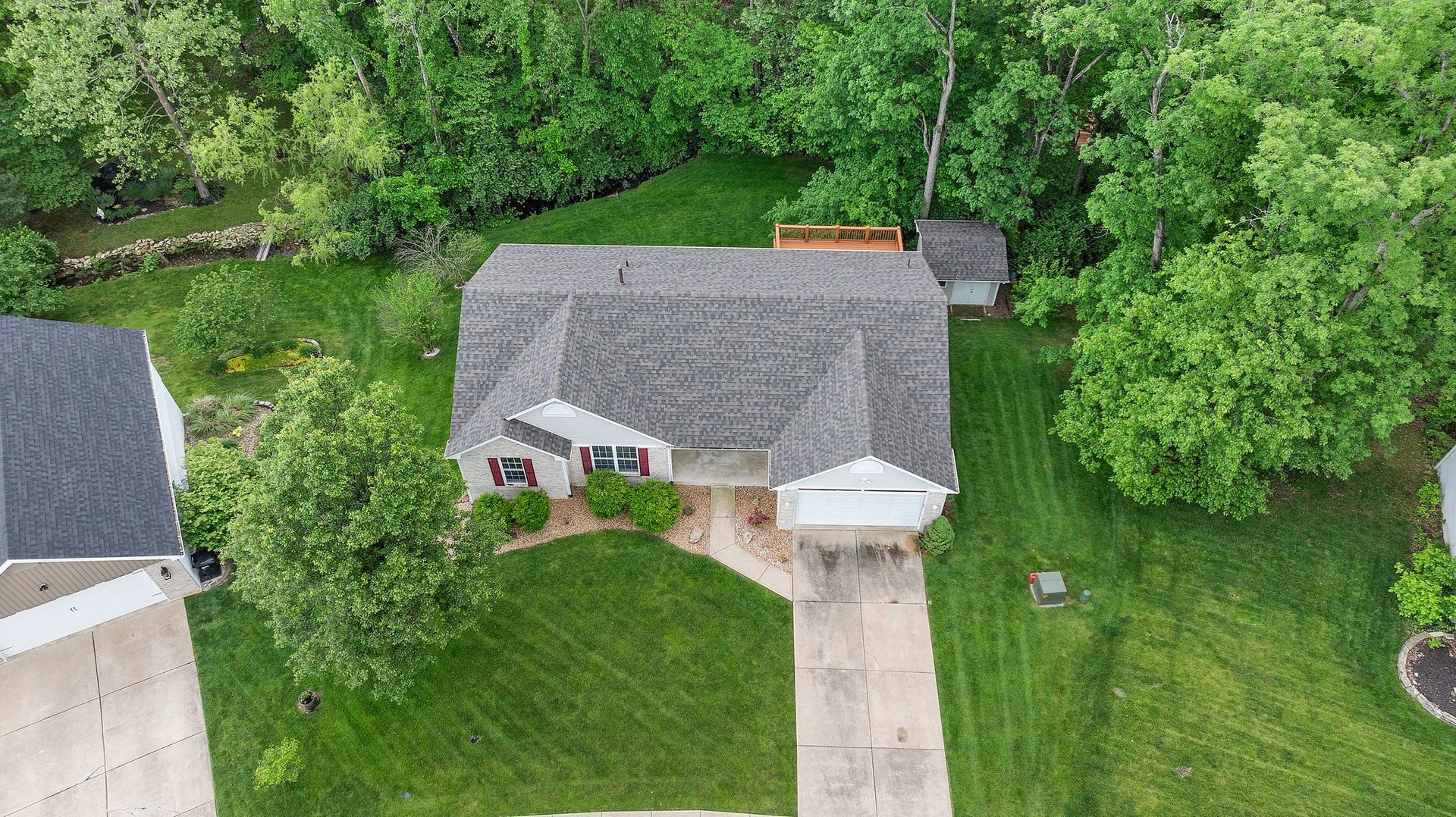 An aerial view of a house surrounded by trees and grass.