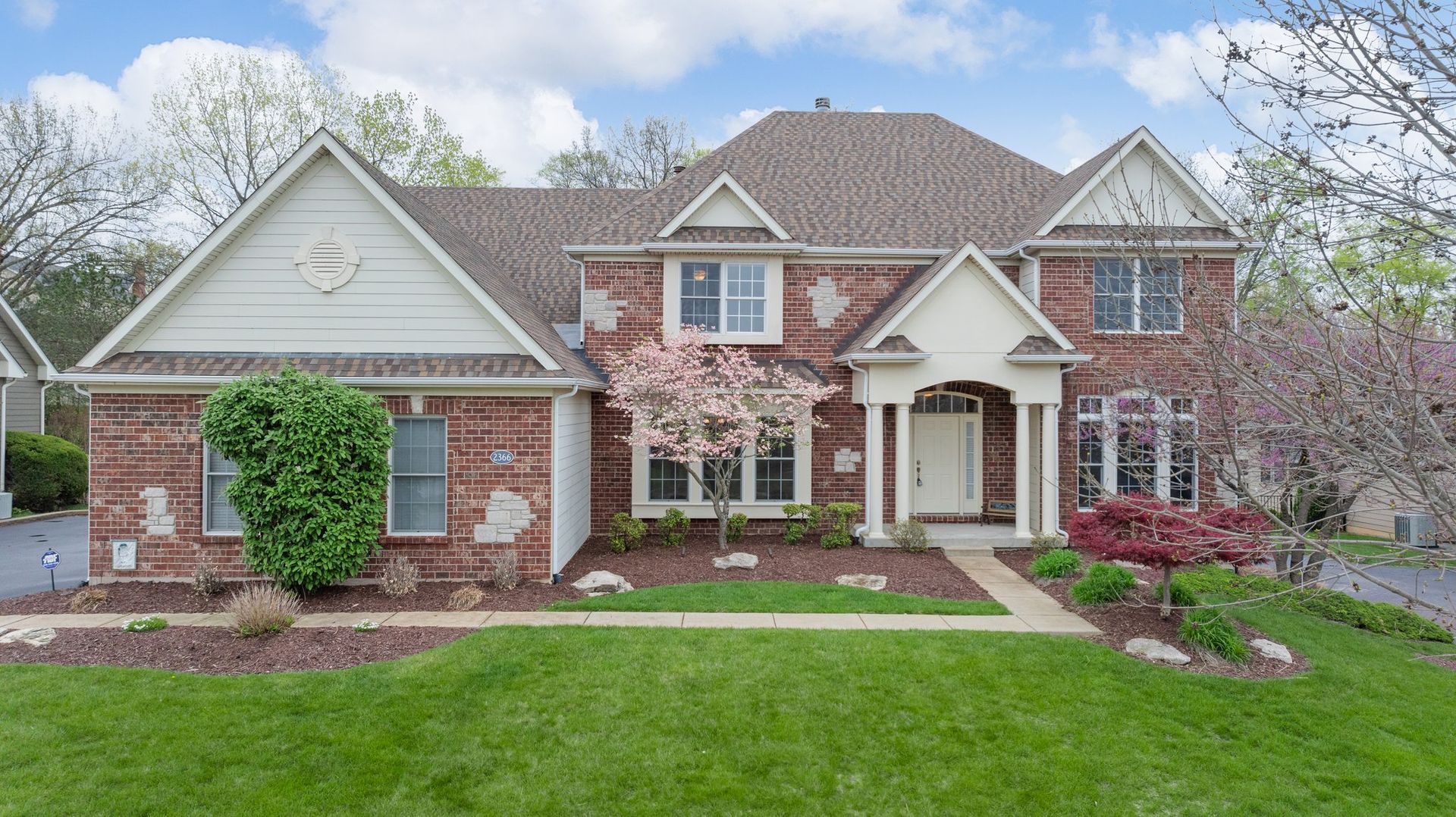 A large brick house with a large lawn in front of it