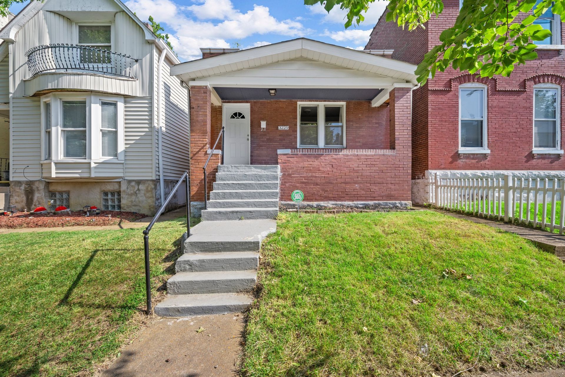 A brick house with stairs leading up to it is for sale.