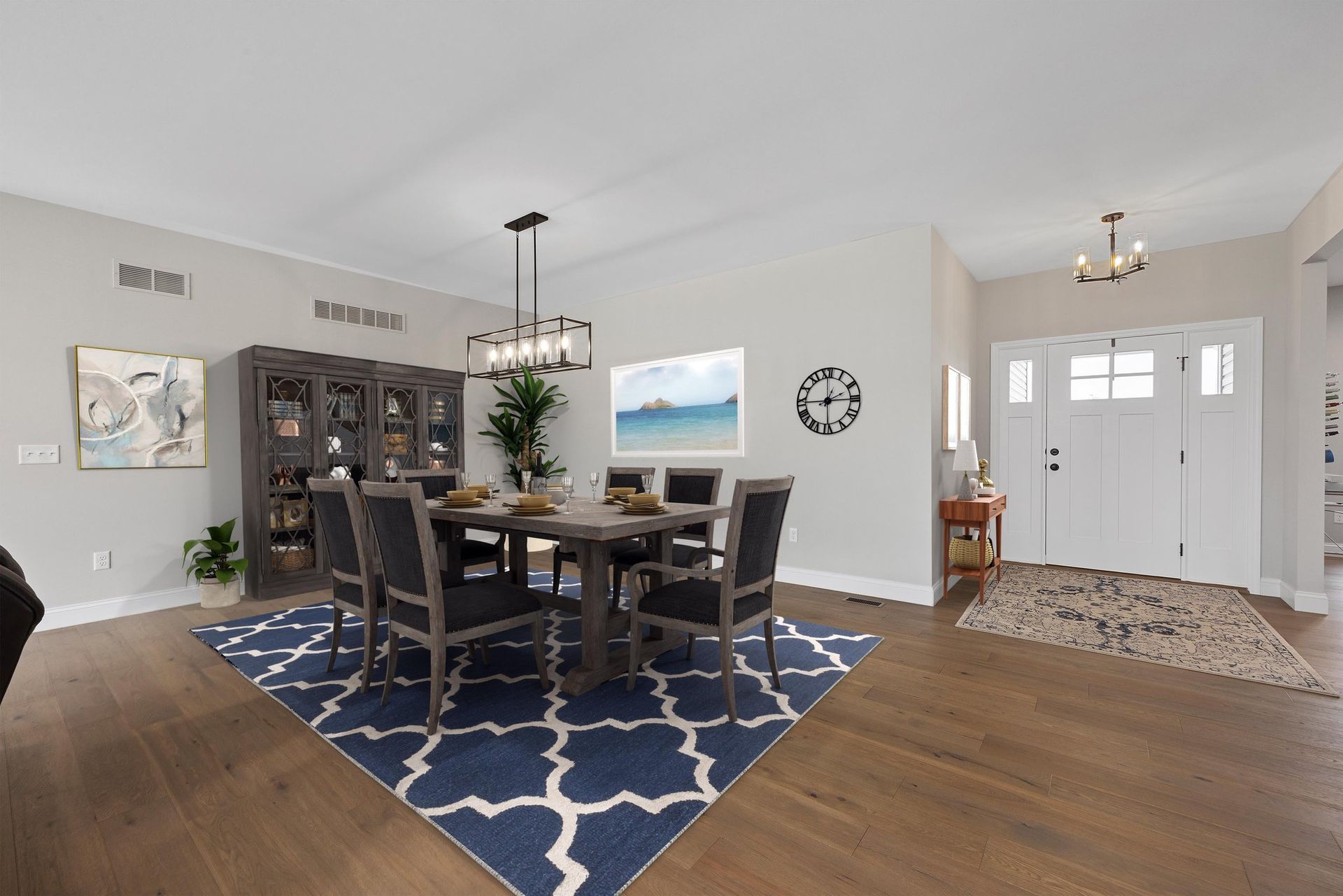 A dining room with a table and chairs and a blue rug.