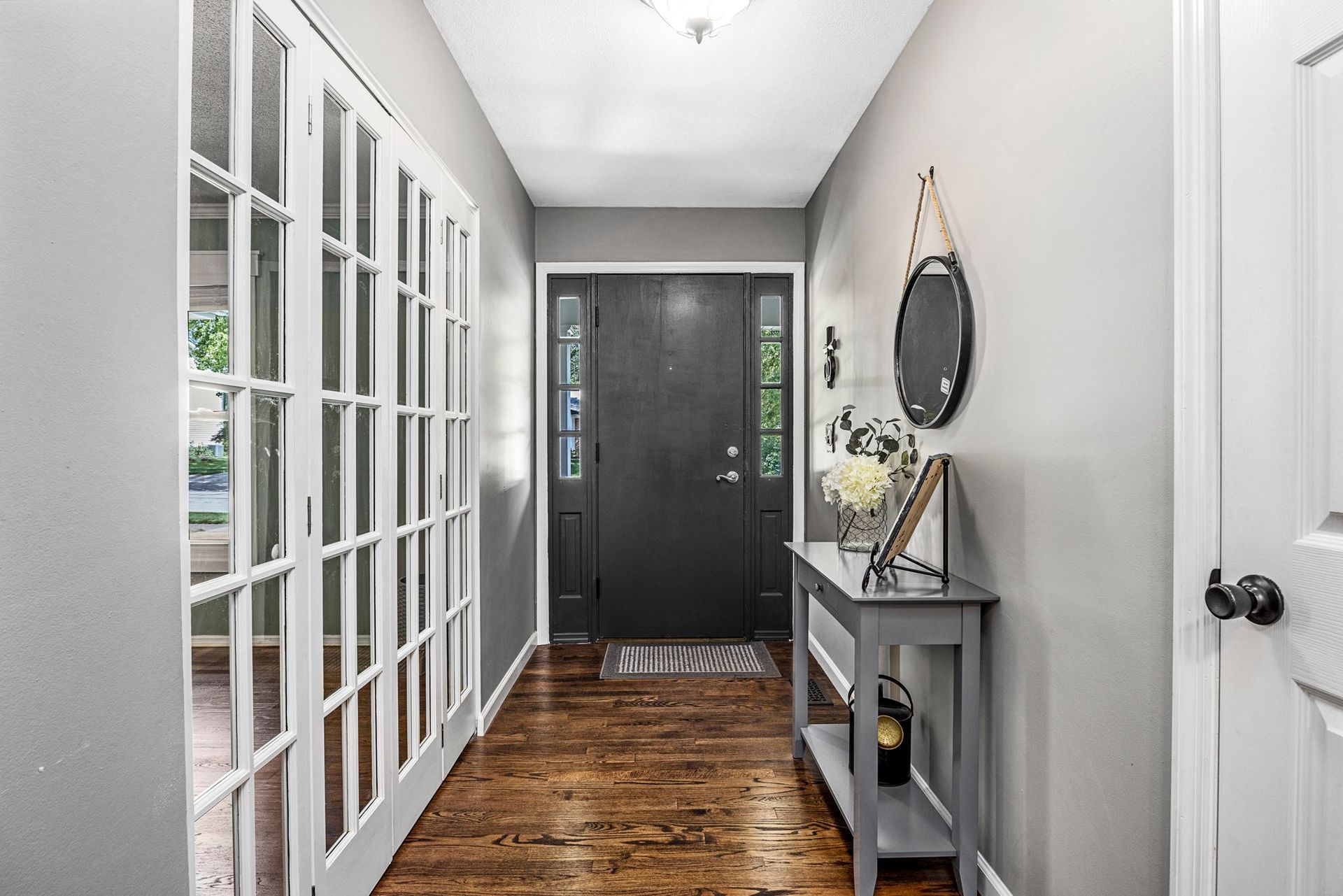 A hallway in a house with a black door and a table.