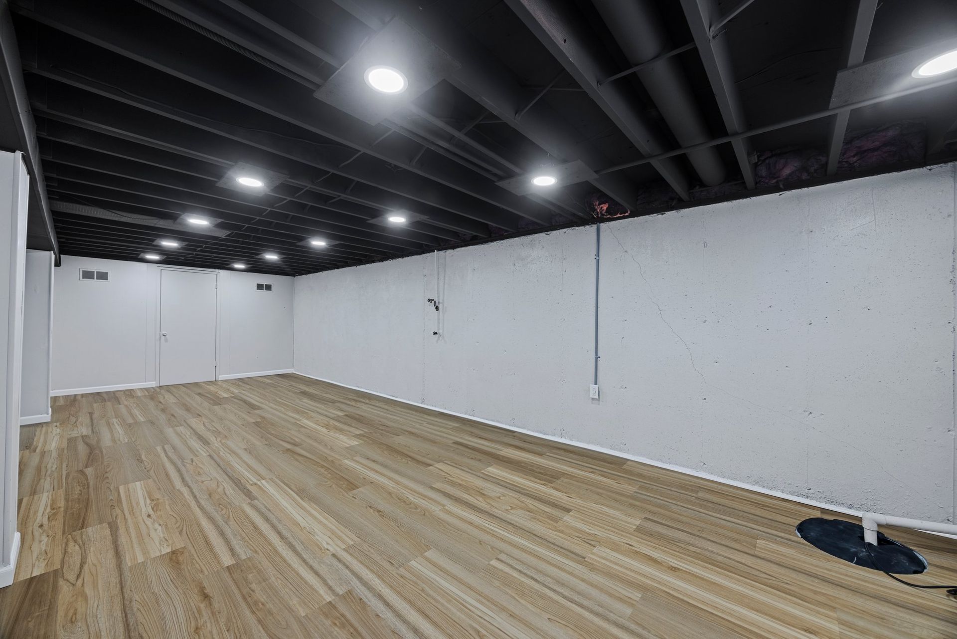 A large empty room with wooden floors and white walls.