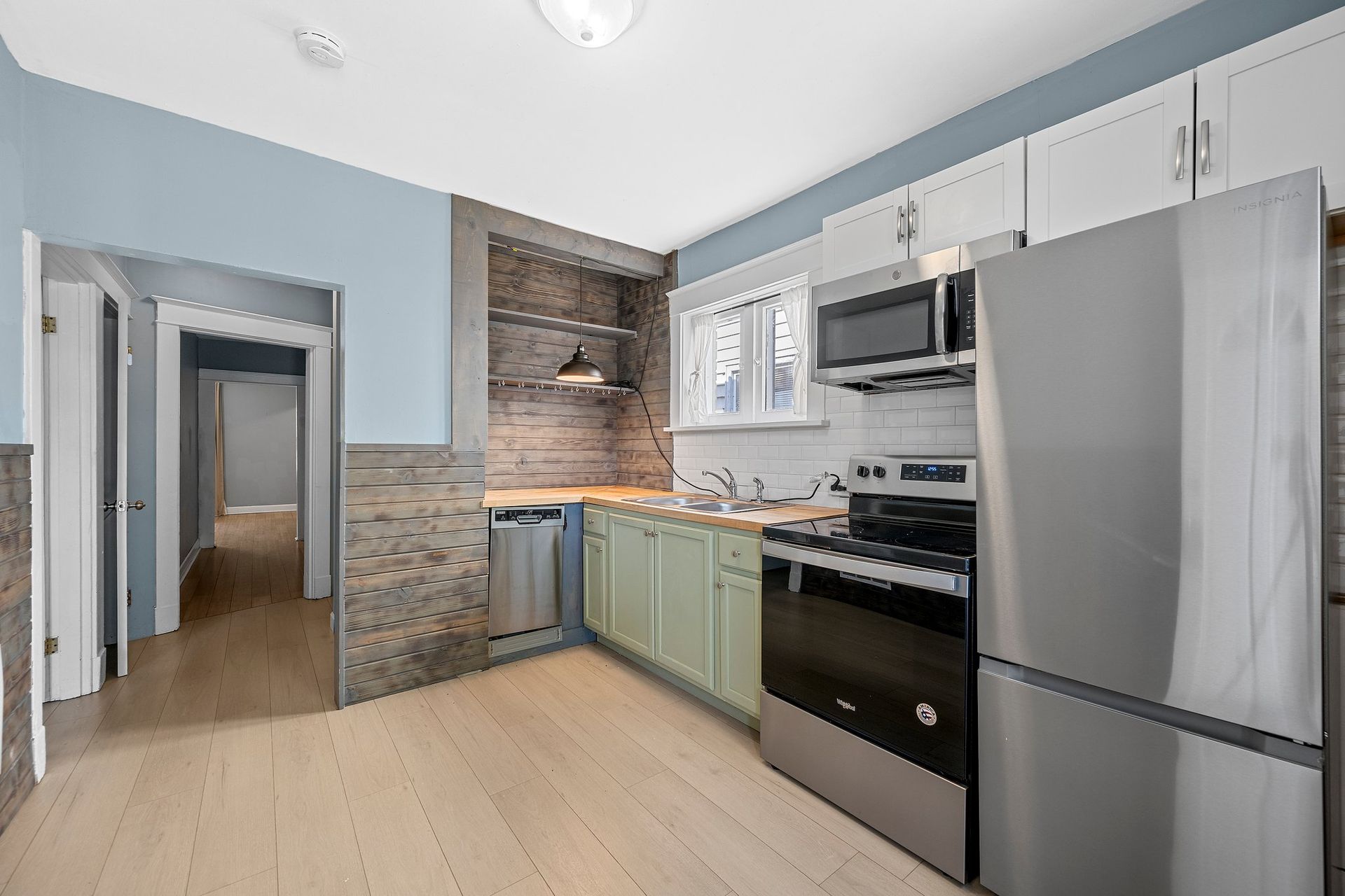A kitchen with stainless steel appliances and green cabinets.
