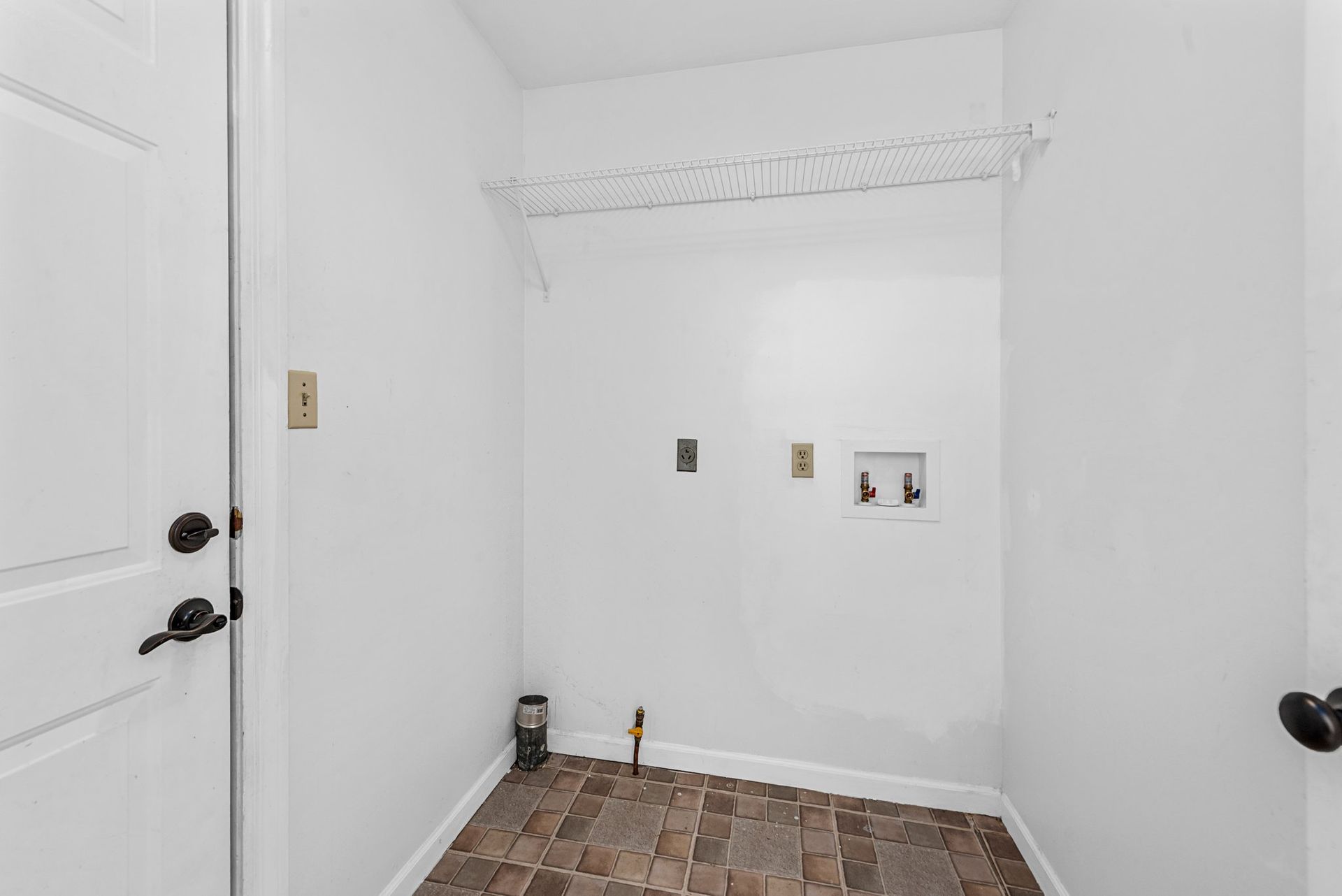 A laundry room with a wooden floor and white walls.