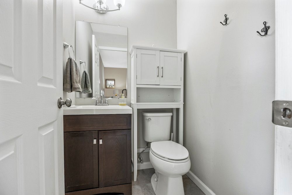 A bathroom with a toilet , sink and mirror.