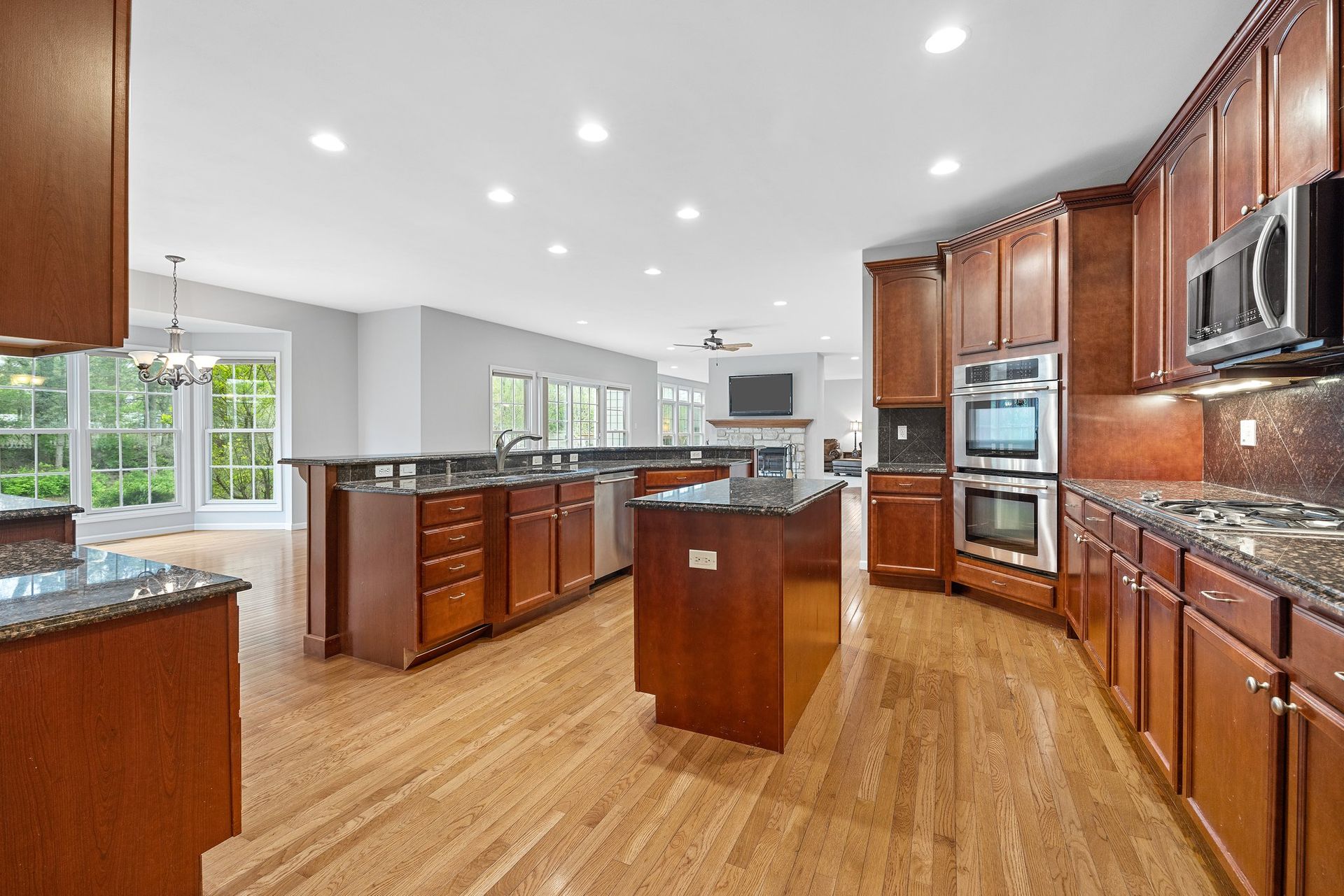 A large kitchen with wooden cabinets , granite counter tops , and stainless steel appliances.