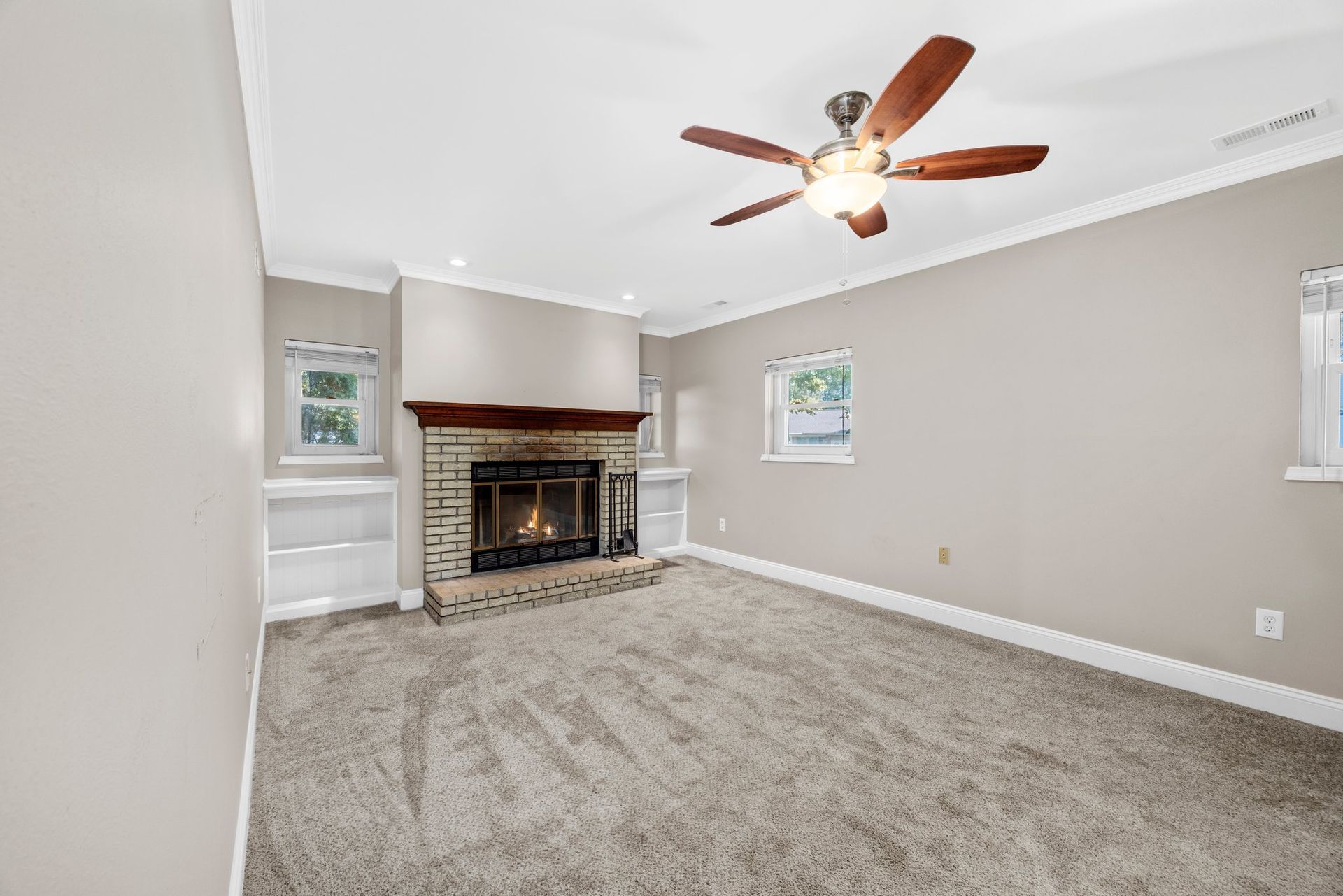A living room with a fireplace and a ceiling fan.