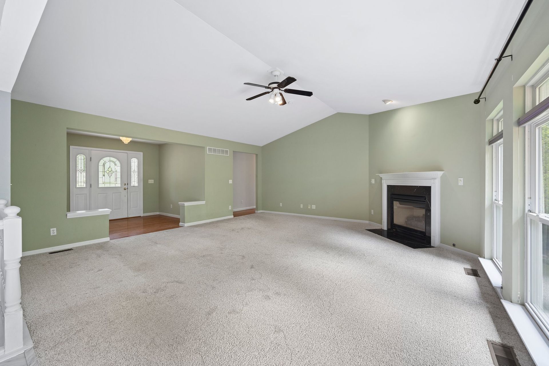 An empty living room with a fireplace and ceiling fan.