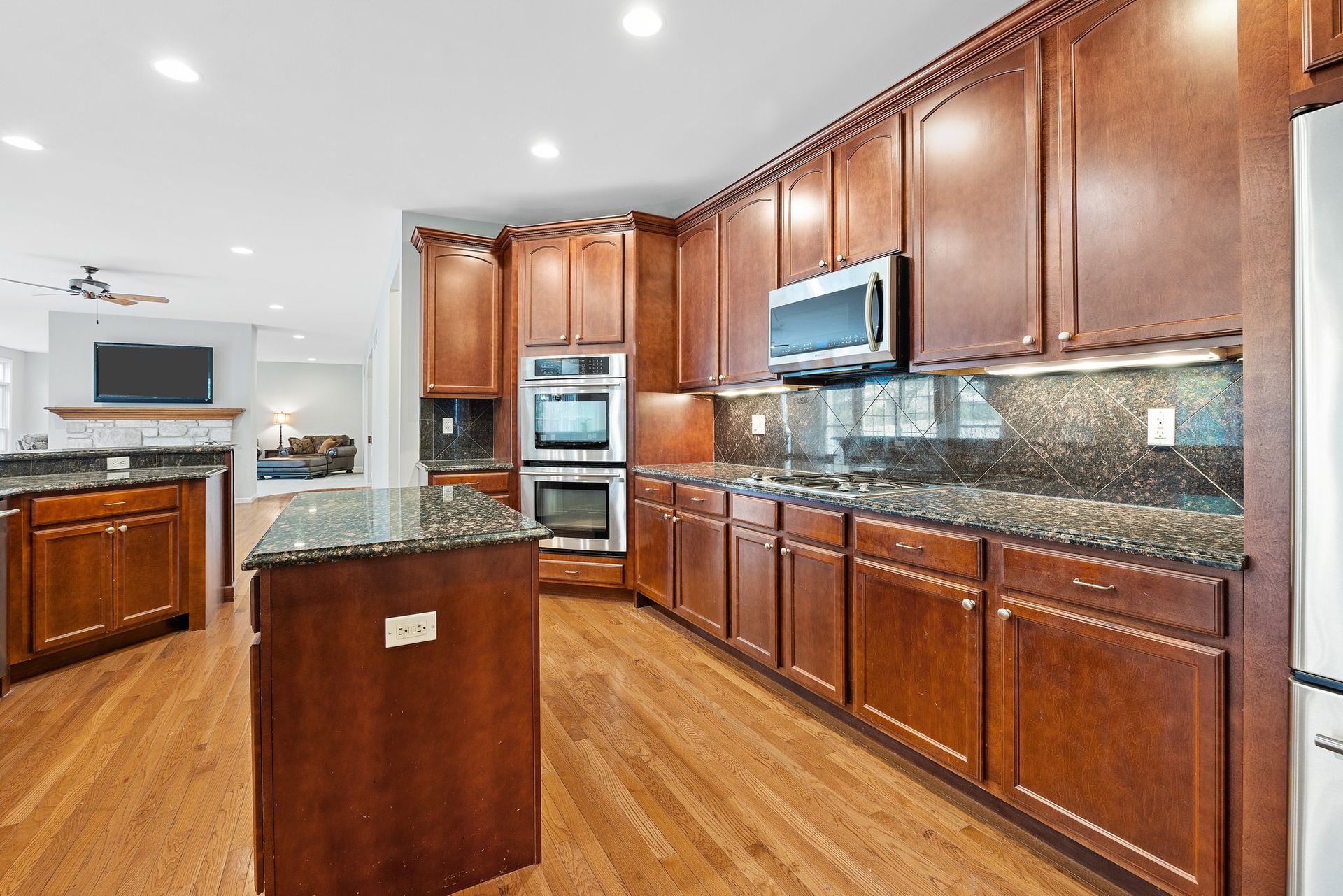 A kitchen with wooden cabinets , granite counter tops , and stainless steel appliances.