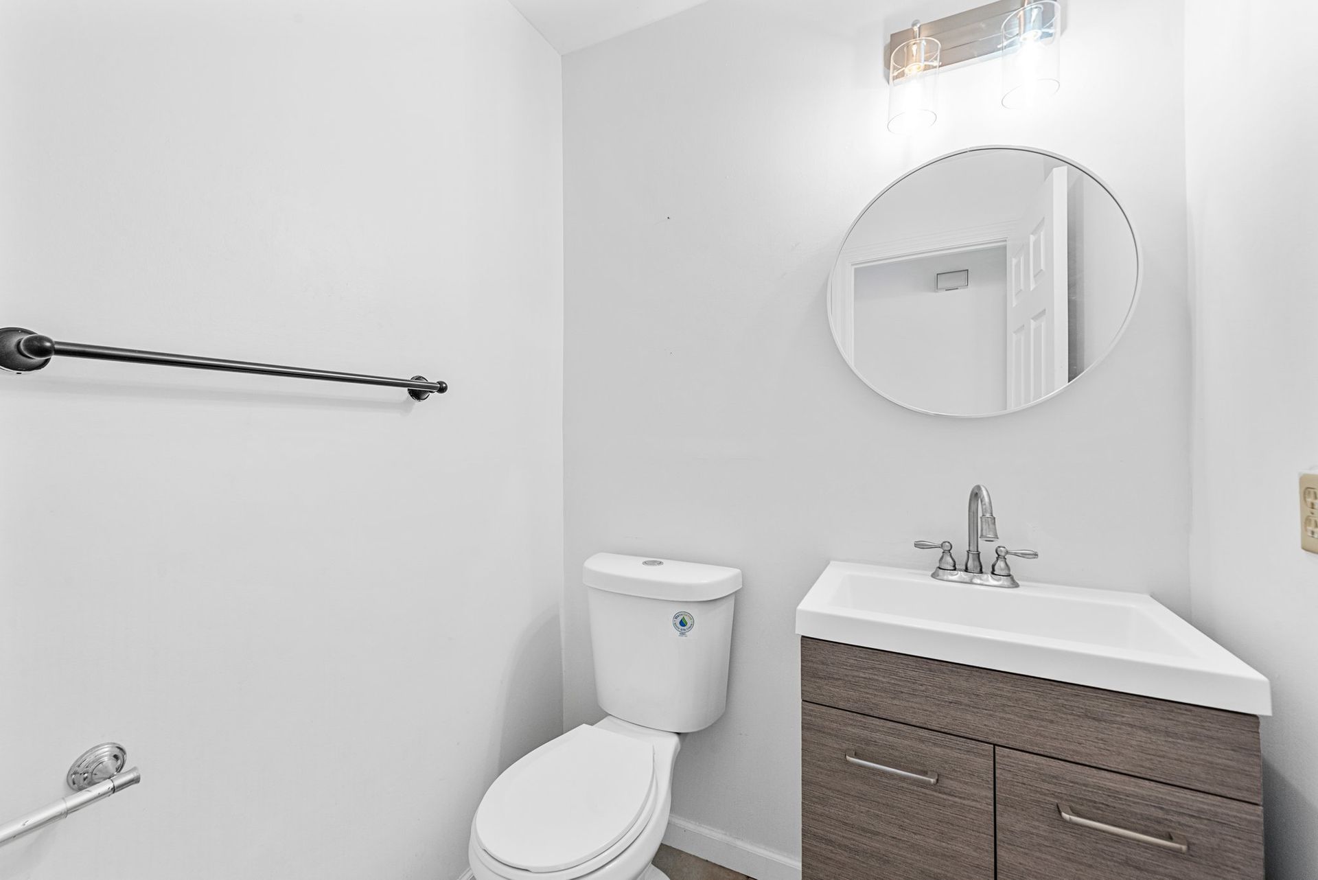 A bathroom with a toilet , sink and mirror.