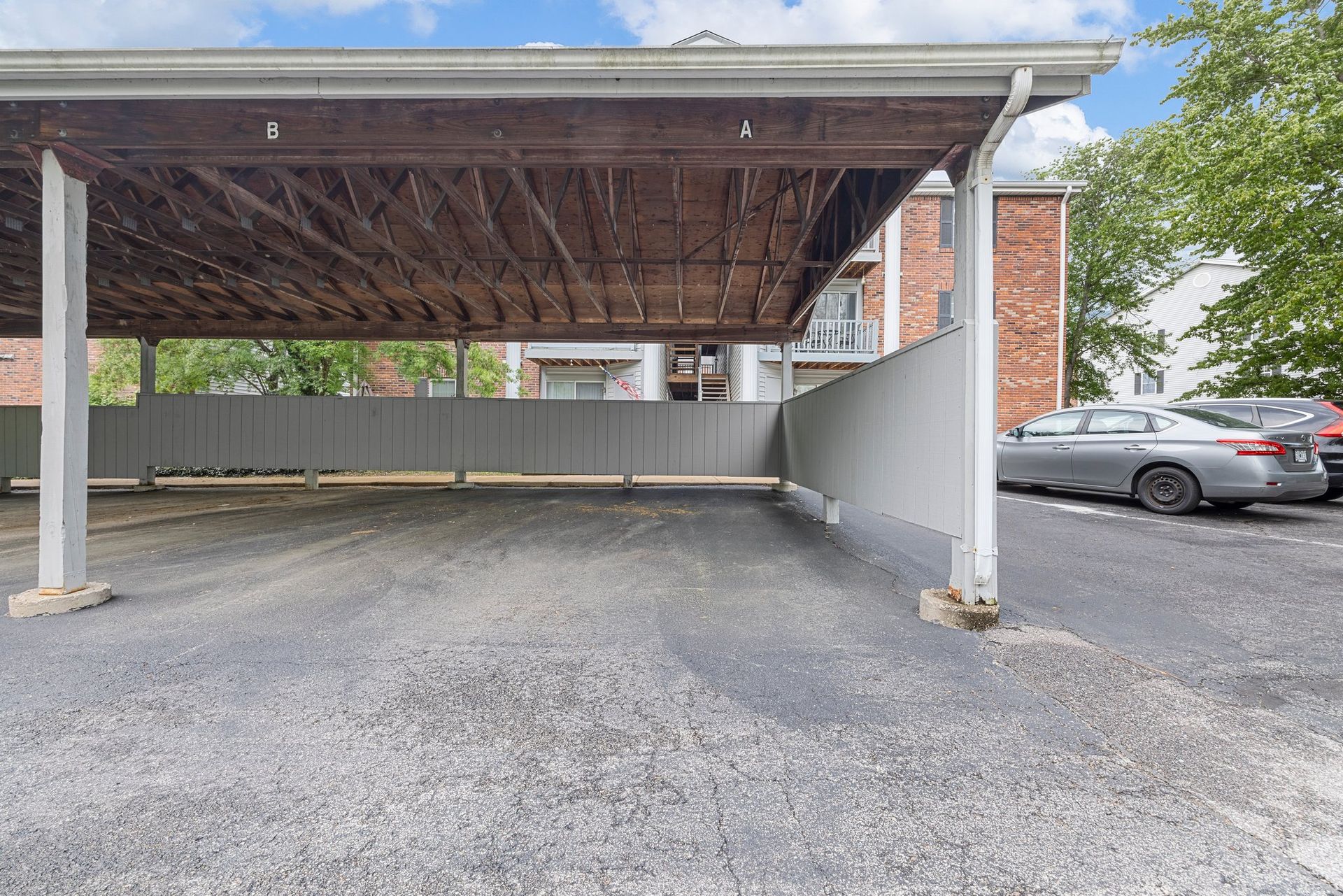 A carport with cars parked underneath it in a parking lot.