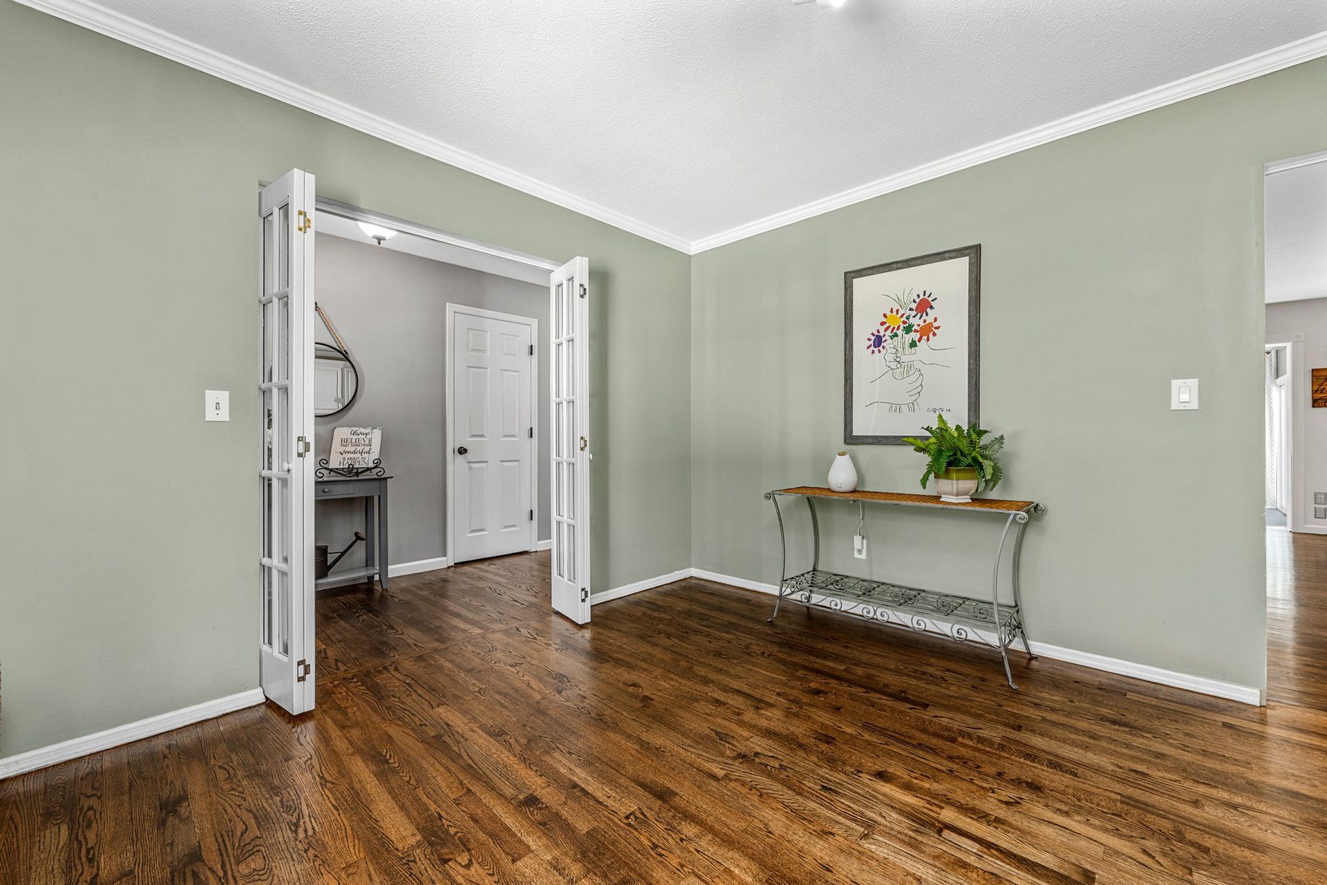 A living room with hardwood floors , a table and a picture on the wall.