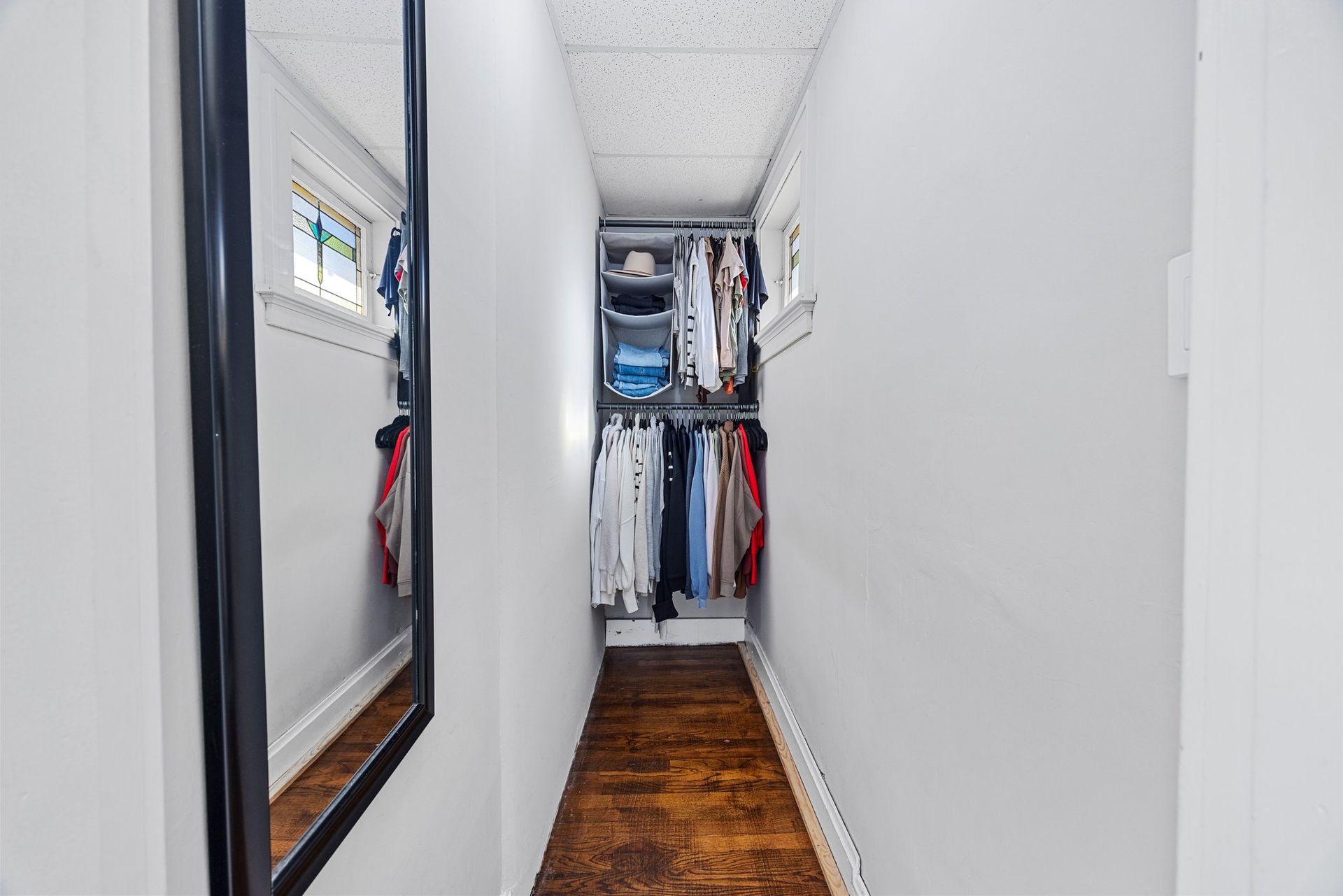 A walk in closet with a large mirror on the wall.