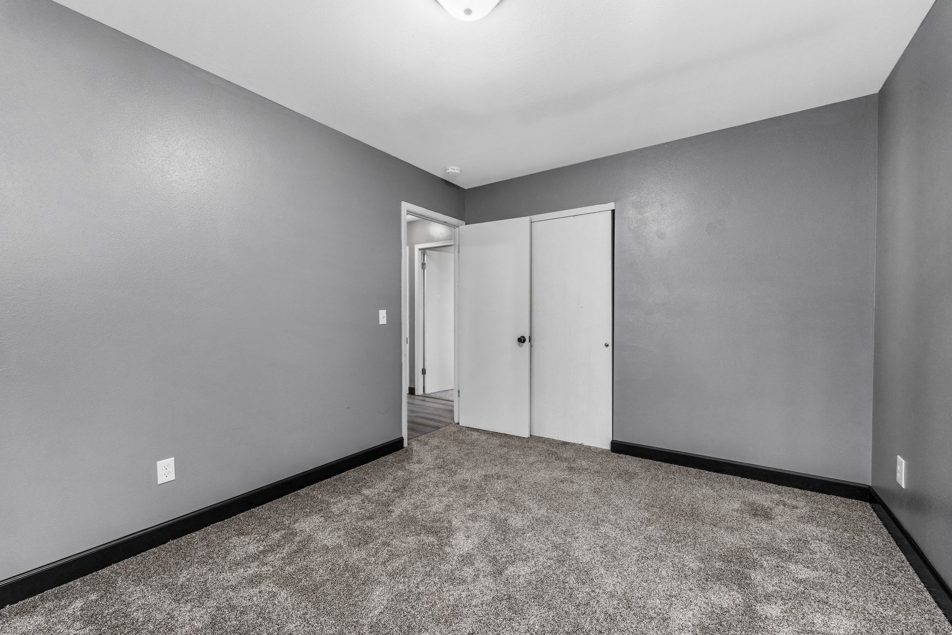 An empty bedroom with gray walls and a gray carpet.