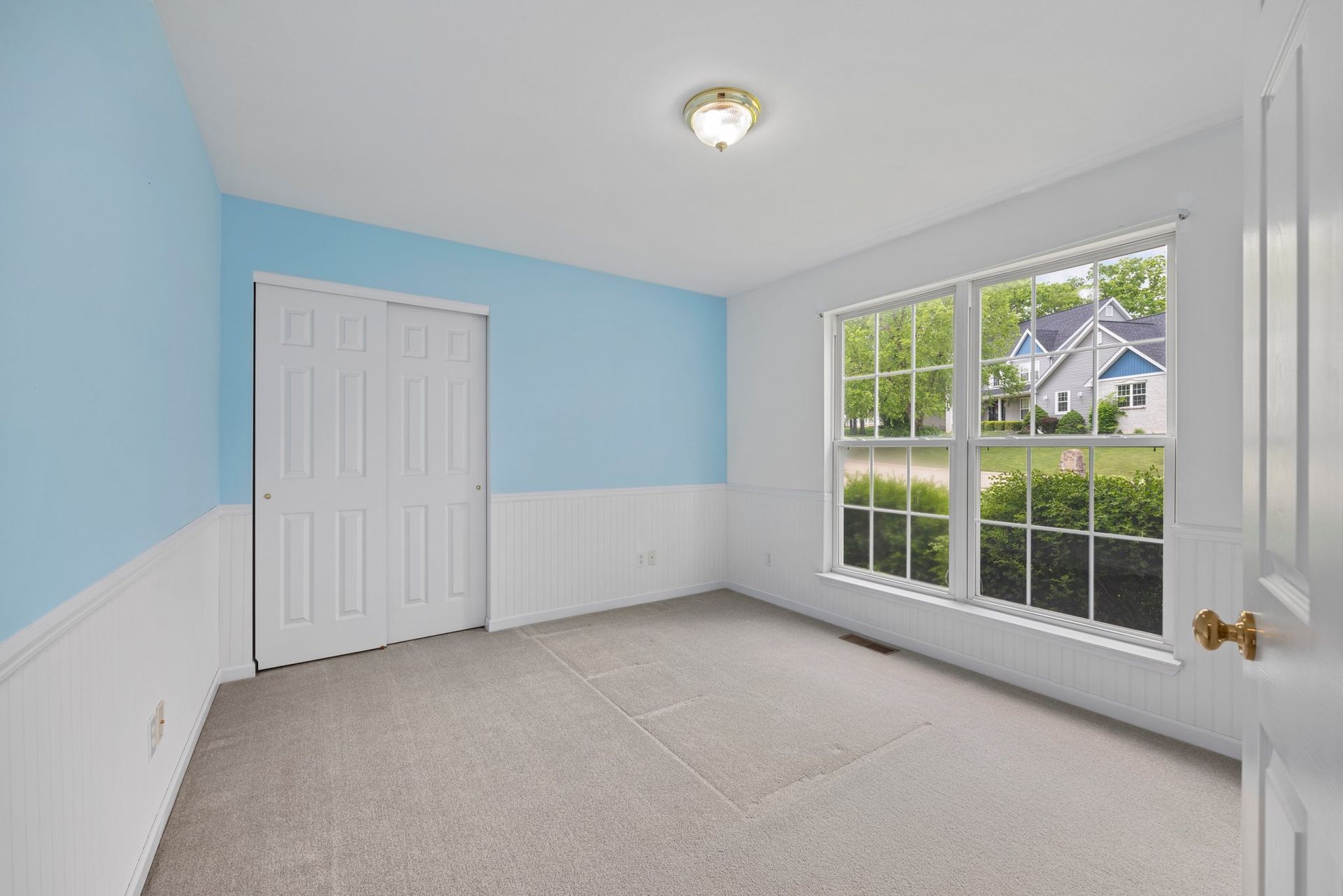 An empty room with blue walls and white trim and two windows.