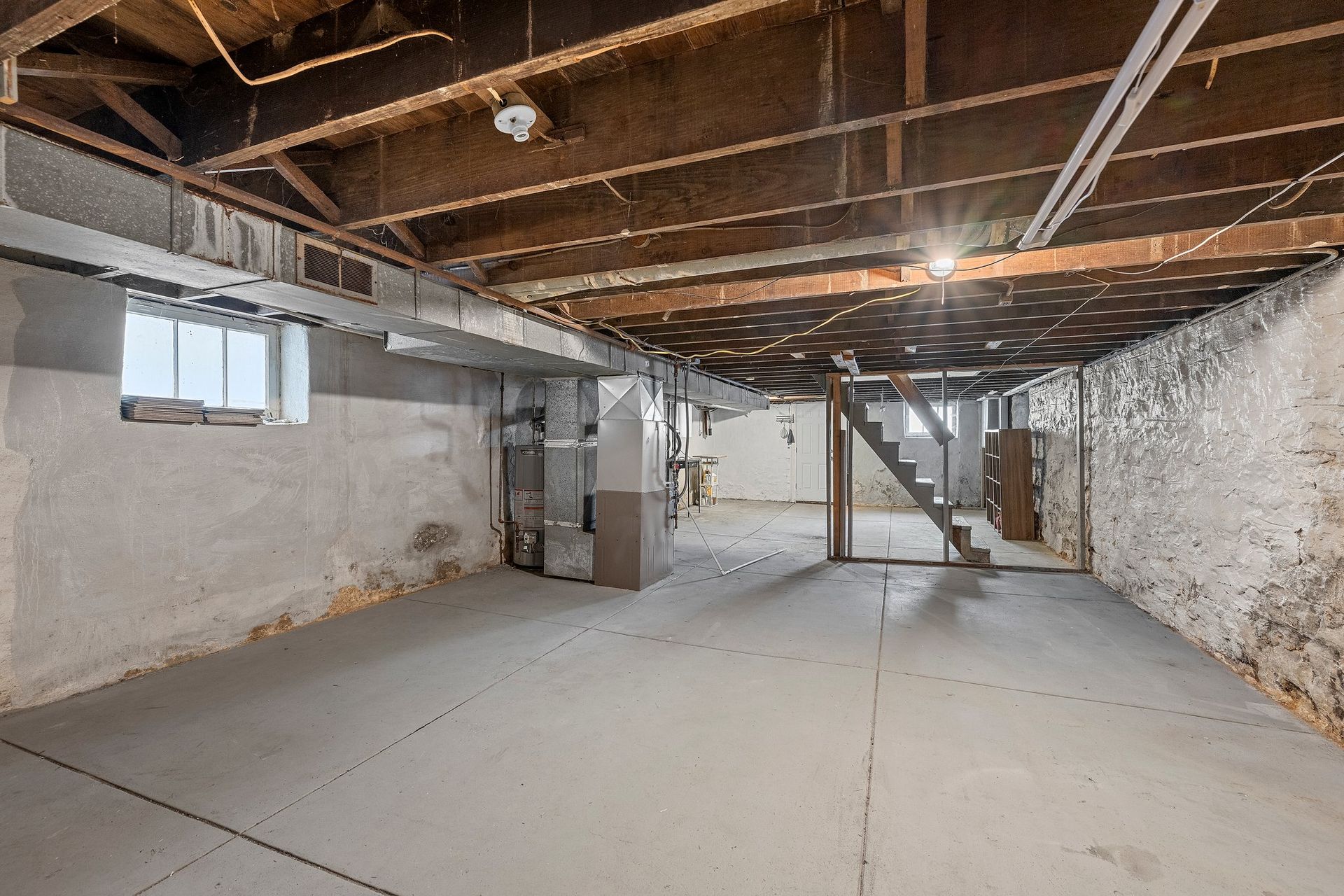 An empty basement with a staircase leading up to the second floor.