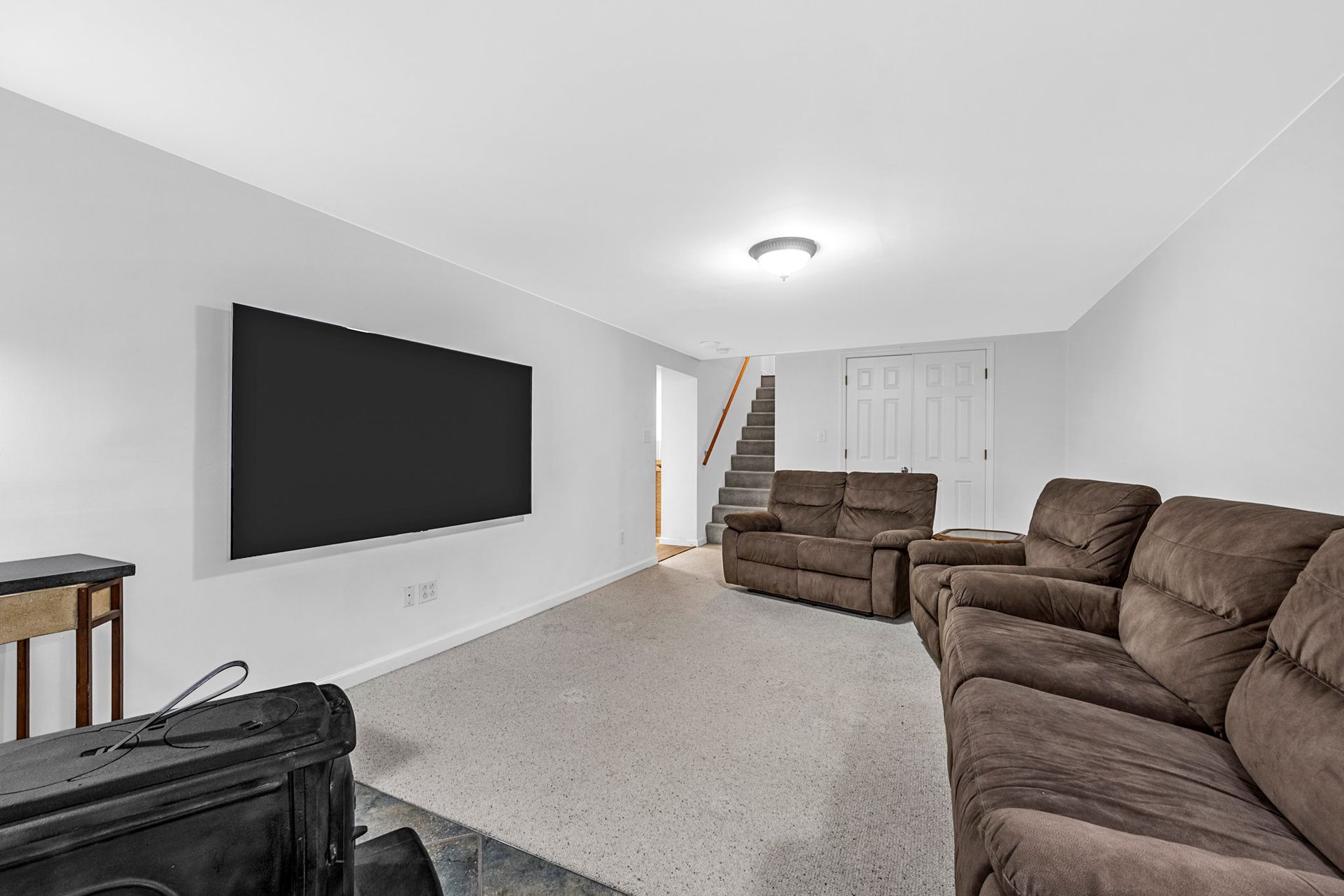 A living room with a couch , chairs and a flat screen tv.