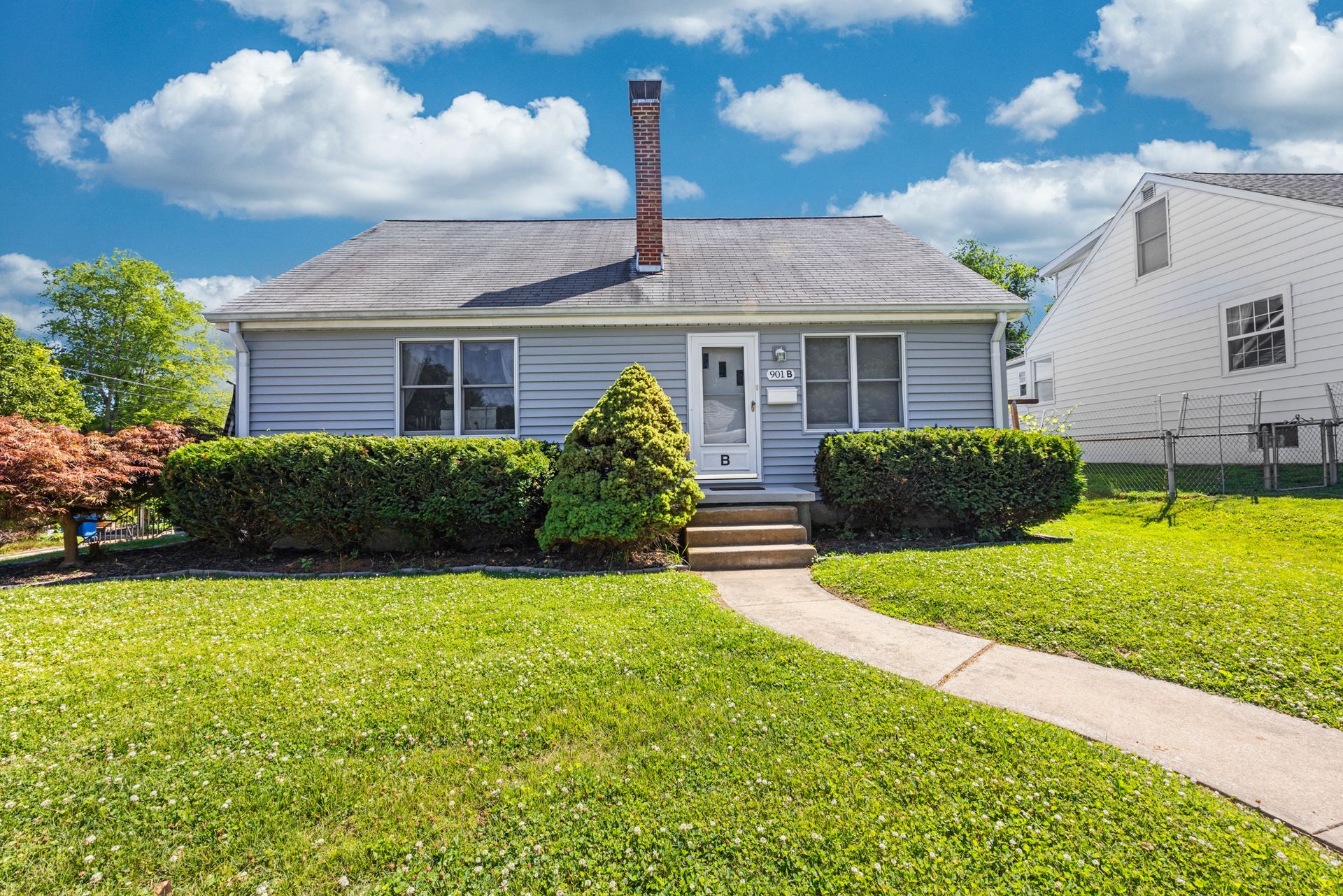 A small house with a lush green lawn and a walkway leading to it.