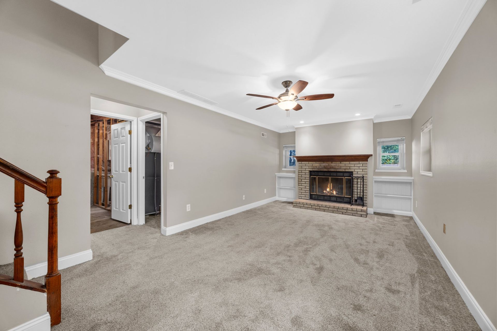 An empty living room with a fireplace and a ceiling fan.