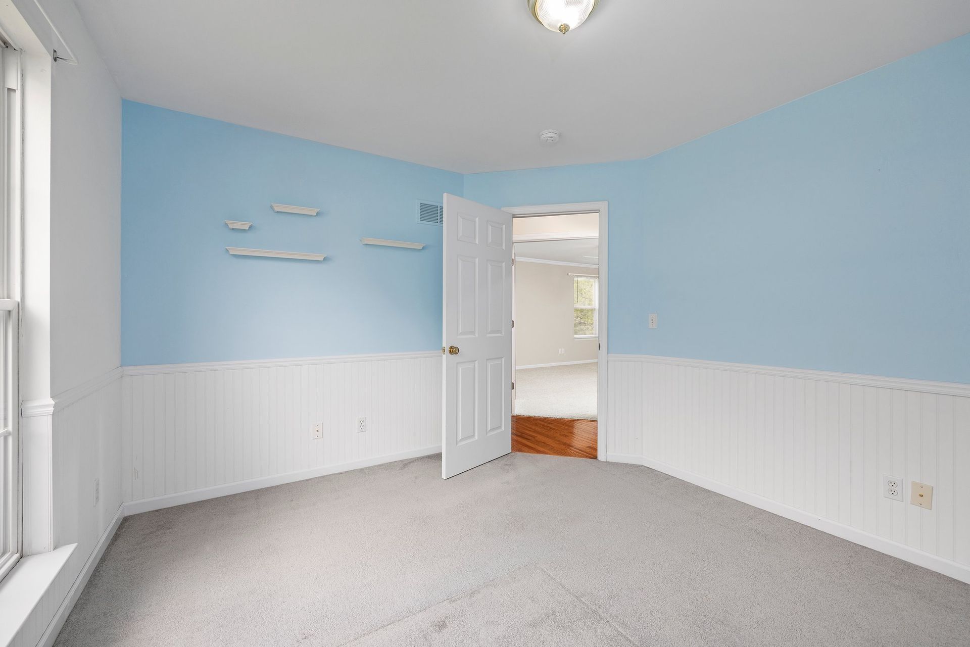 An empty bedroom with blue walls and white trim