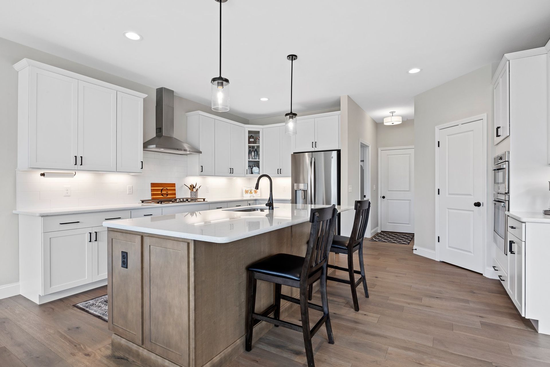 A kitchen with white cabinets , stainless steel appliances , and a large island.