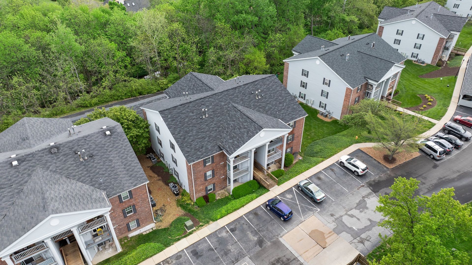 An aerial view of a row of apartment buildings with cars parked in front of them.