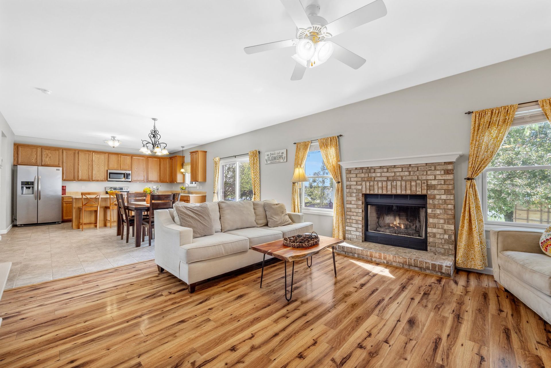 A living room with hardwood floors , a couch , a fireplace and a ceiling fan.