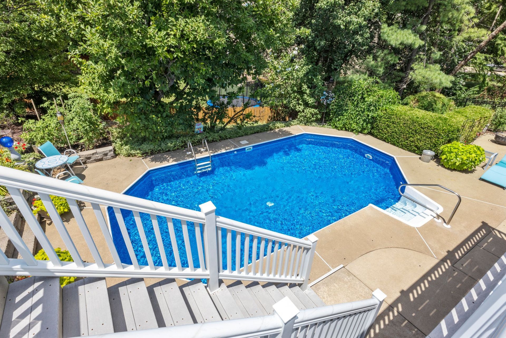 An aerial view of a large swimming pool in a backyard surrounded by trees.