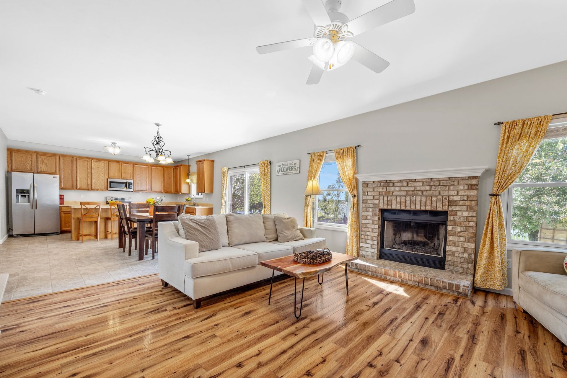 A living room with hardwood floors , a couch , a fireplace and a ceiling fan.