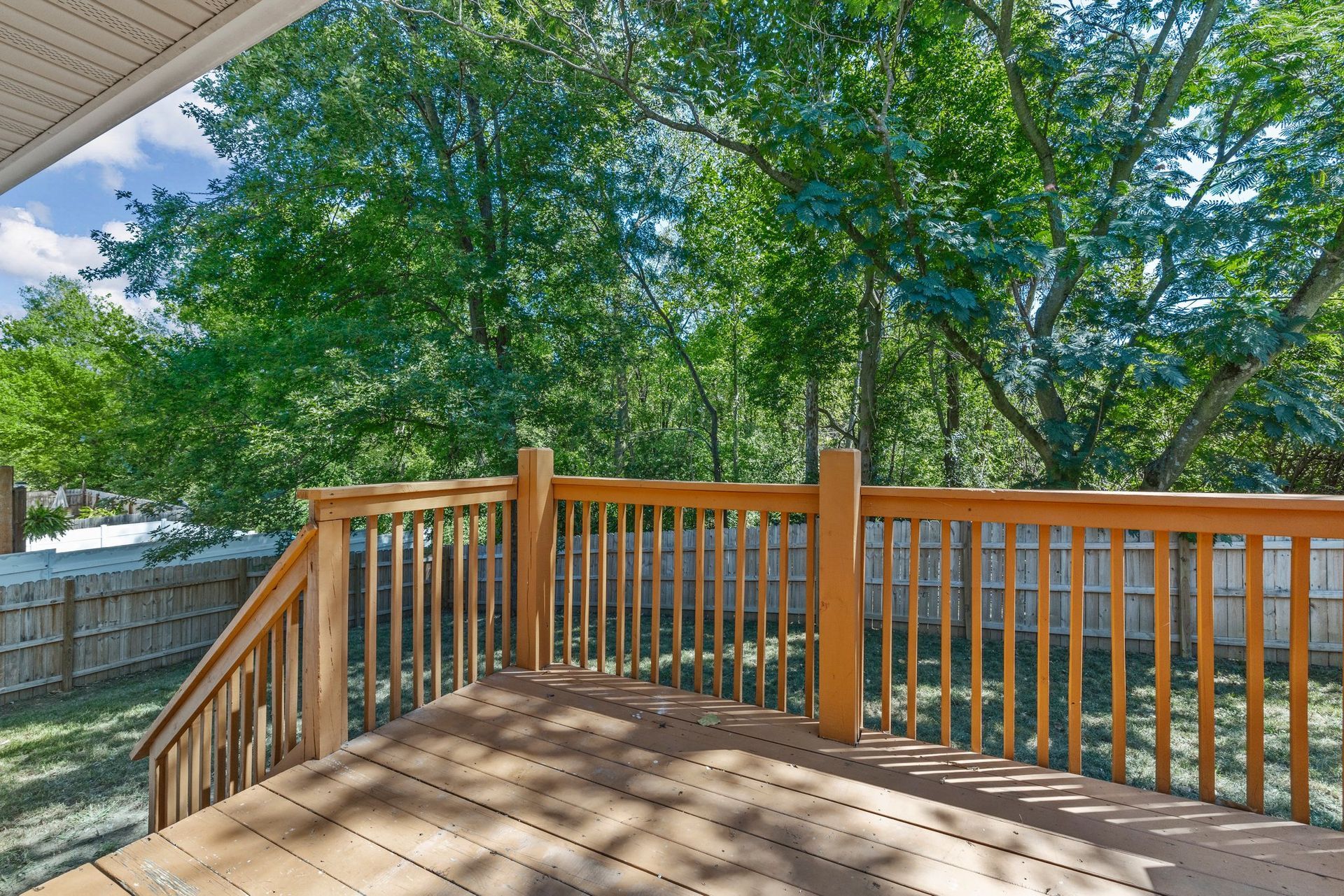 A wooden deck with a railing and trees in the background