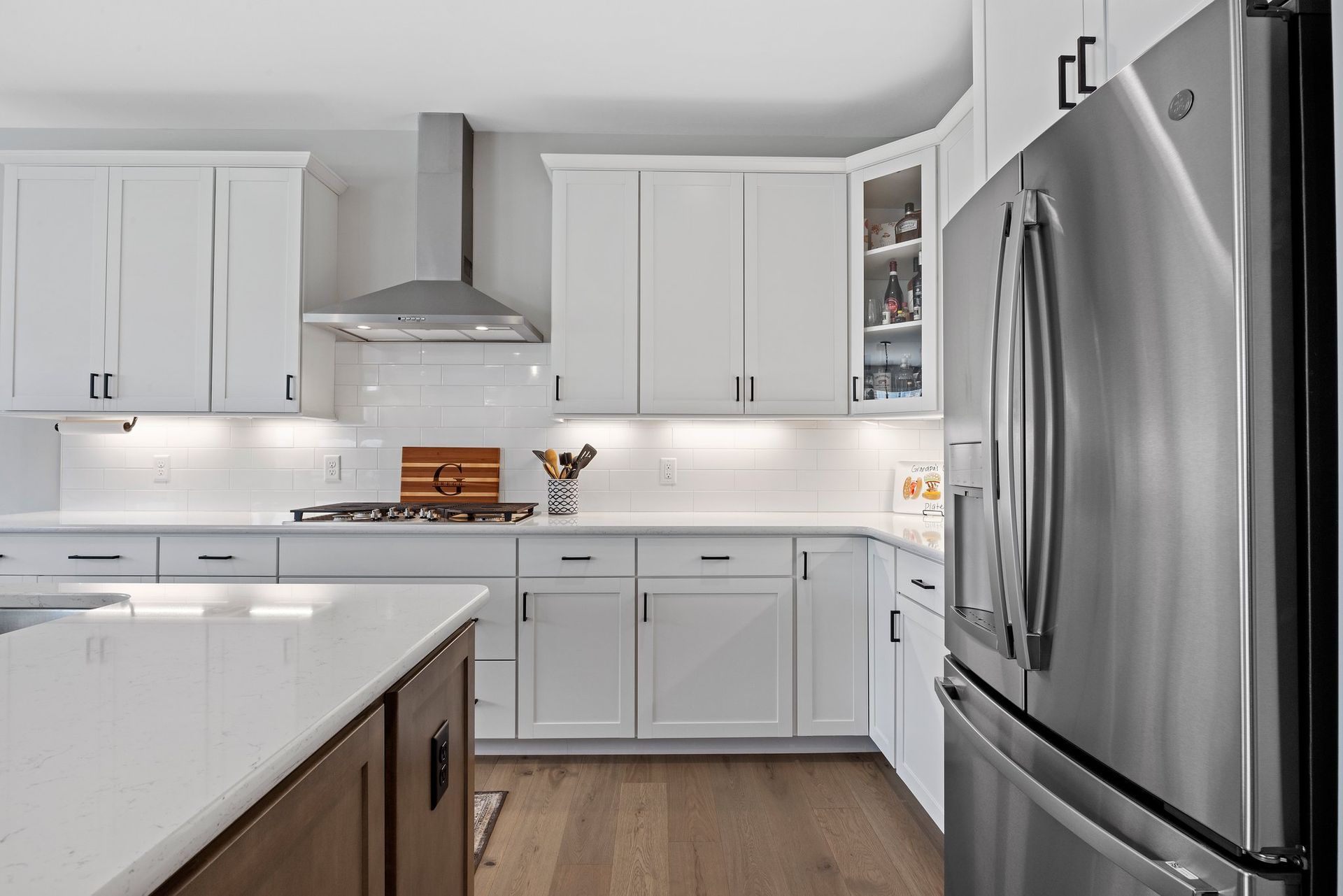 A kitchen with white cabinets and a stainless steel refrigerator.