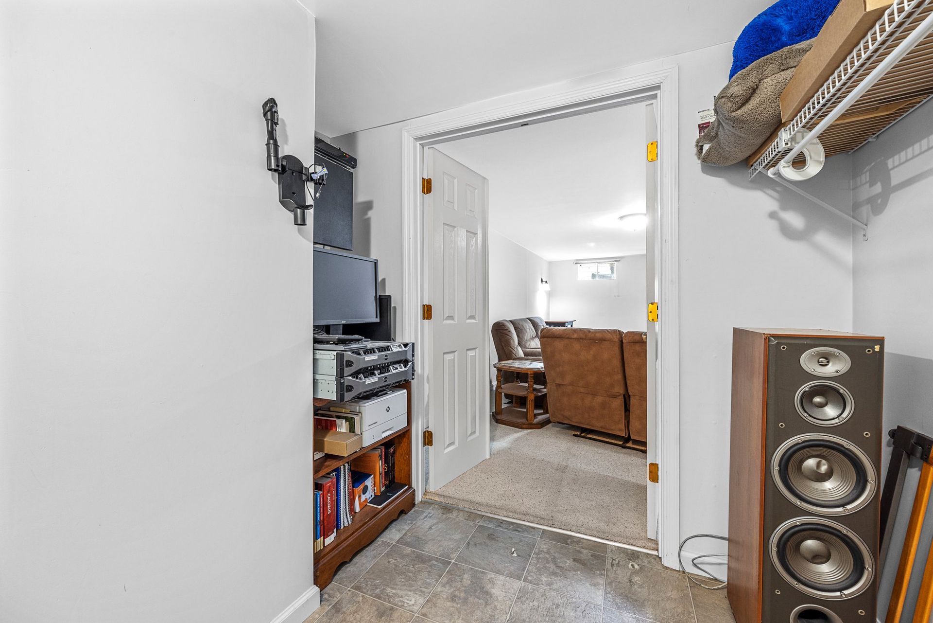 A hallway leading to a living room with a couch and speakers.