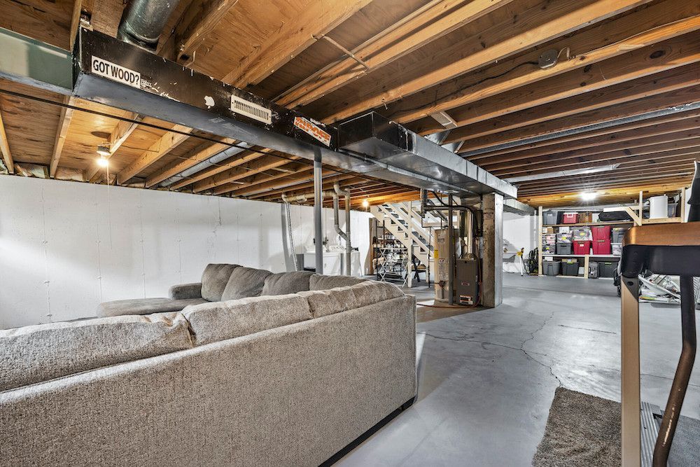 A living room in a basement with a couch and a table.