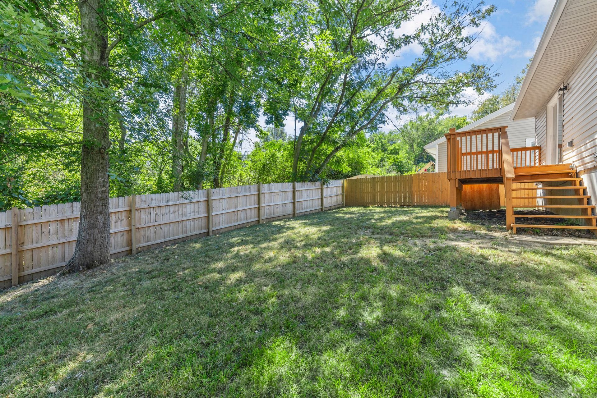 The backyard of a house with a wooden fence and a deck.