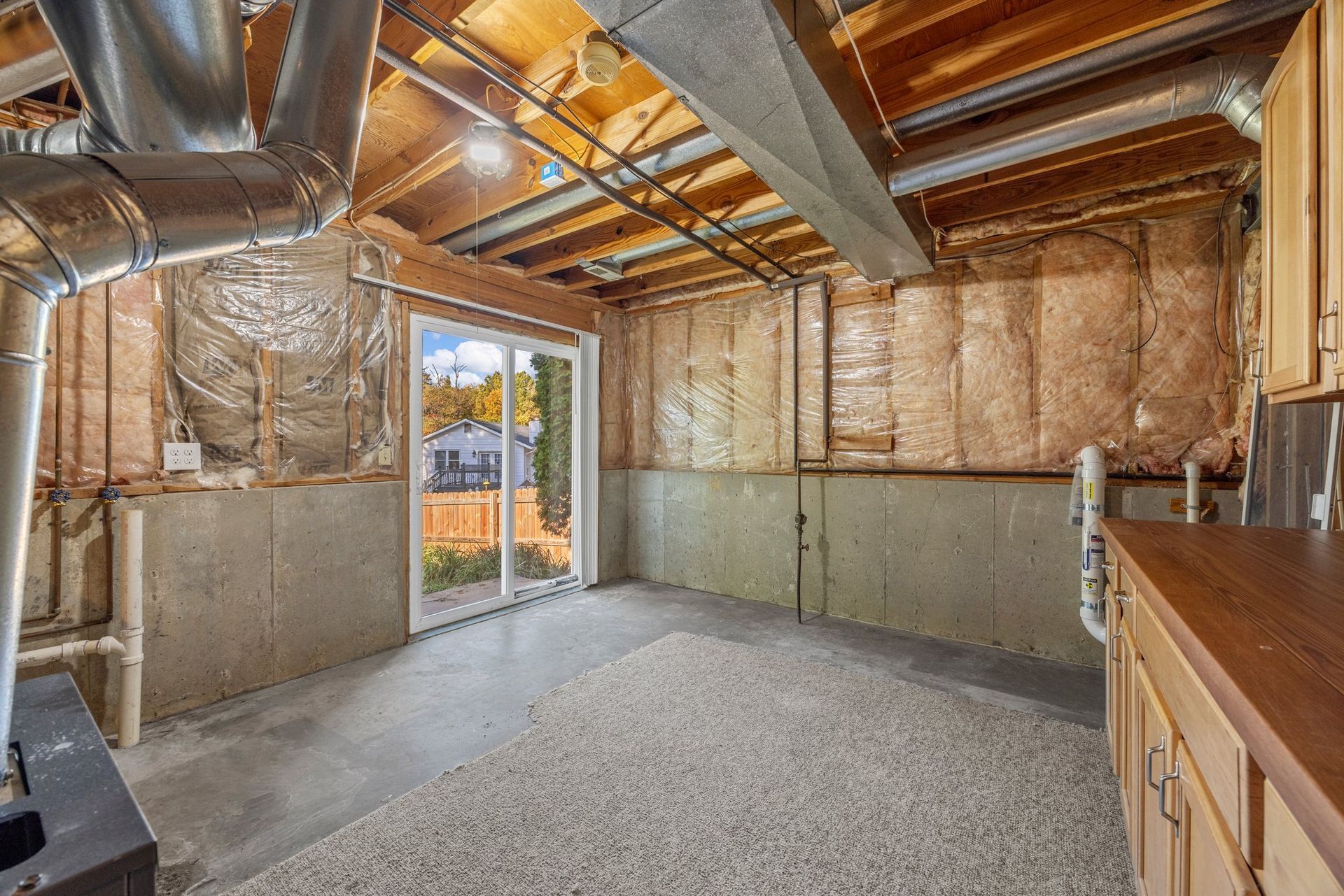 A basement with a lot of insulation and a sliding glass door.