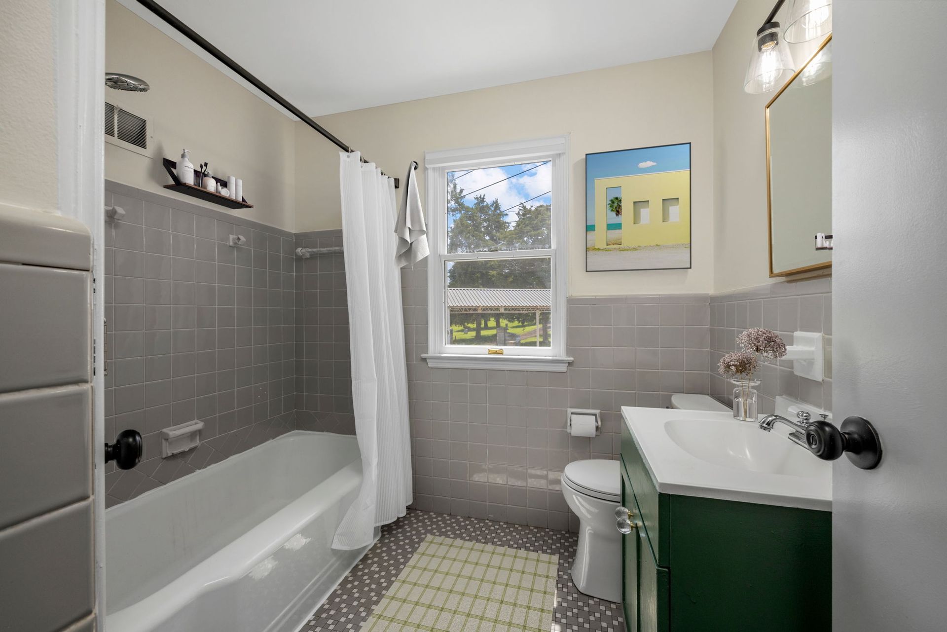 A bathroom with a tub , sink , toilet and window.