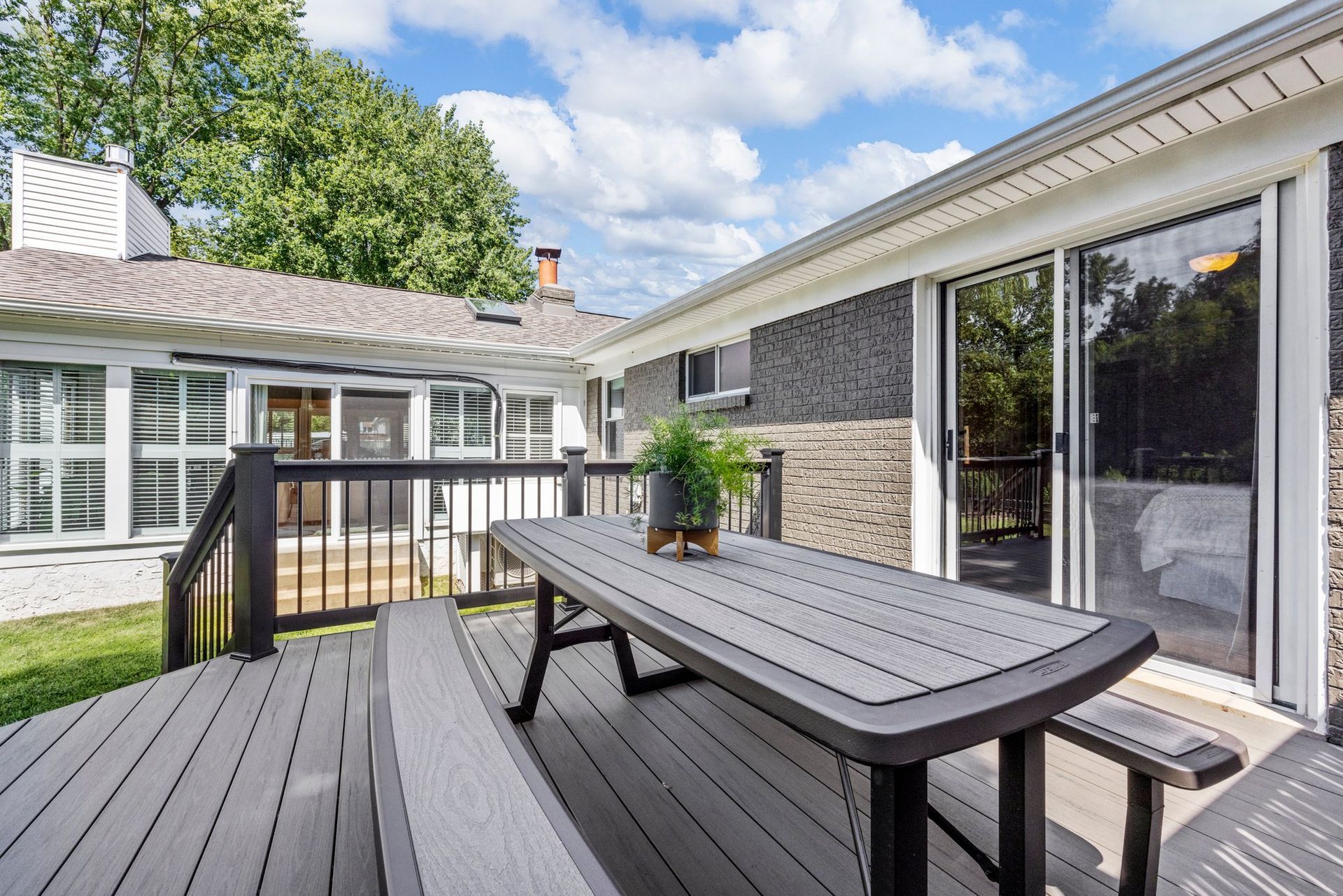 There is a table and benches on the deck of a house.