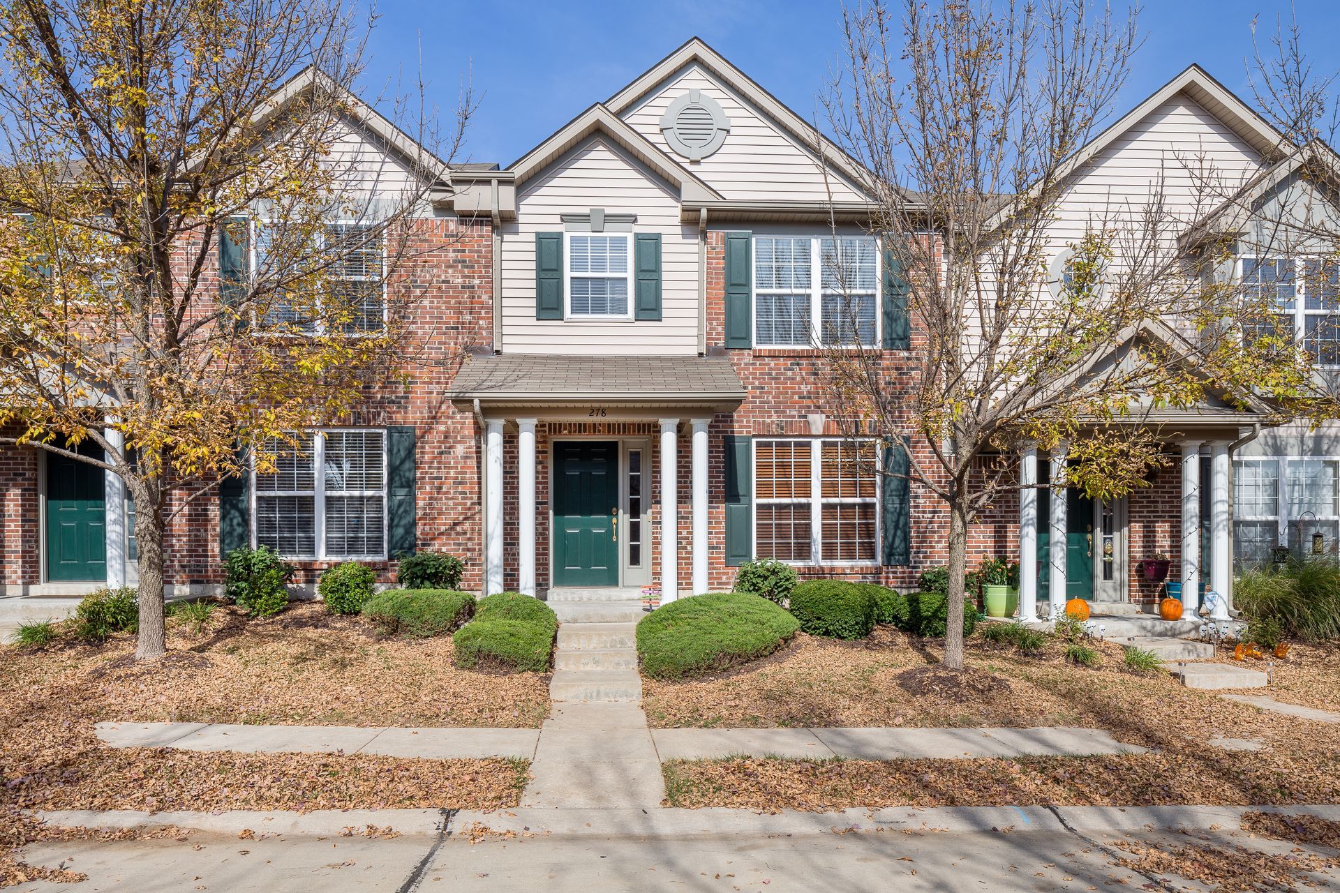A large brick house with white trim and green shutters